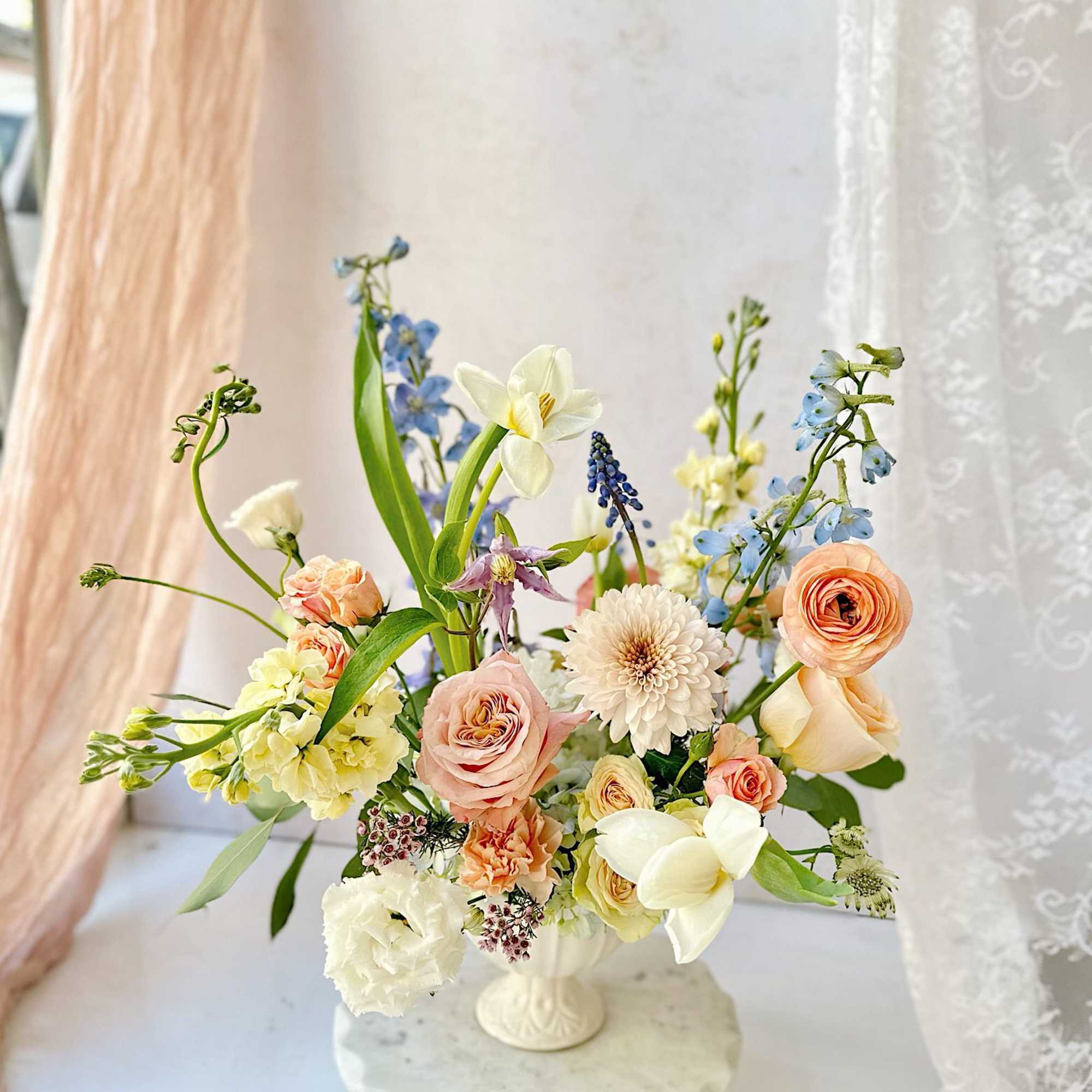 A stunning vase arrangement featuring soft, peachy and white flowers, including roses