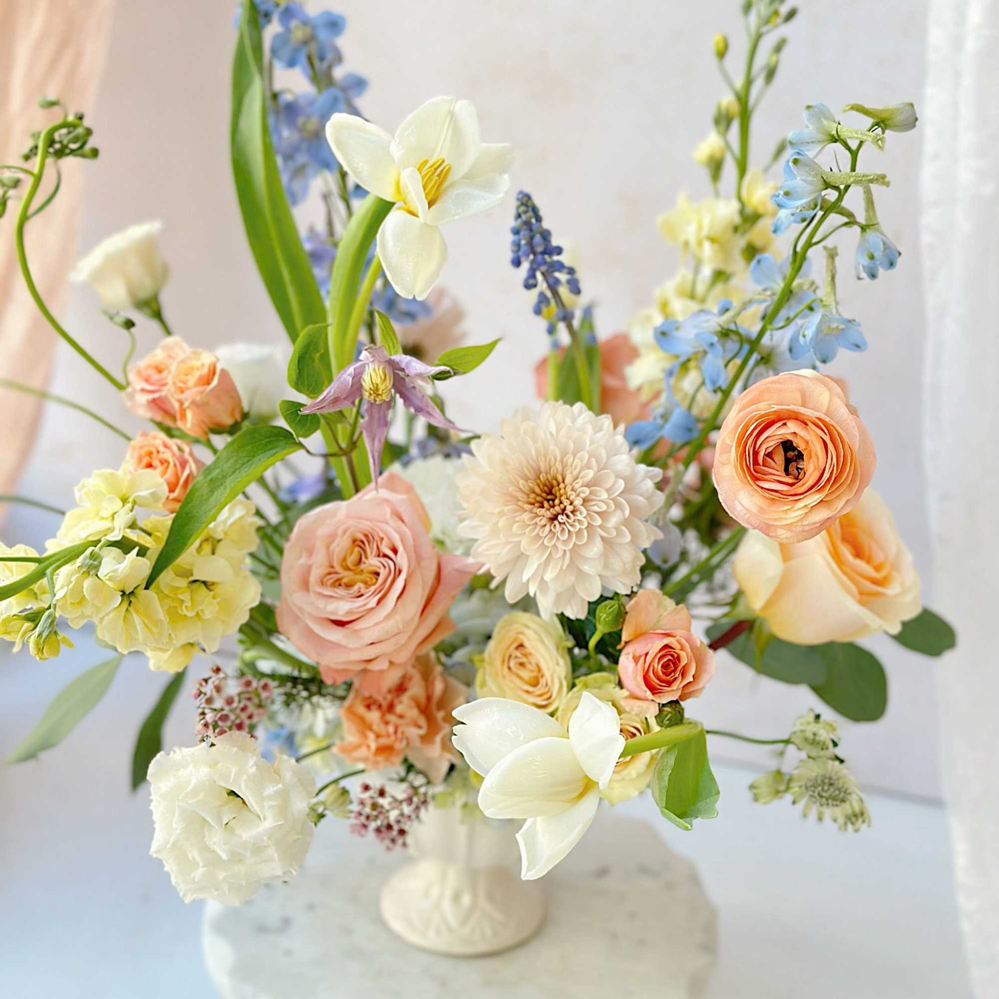 A stunning vase arrangement featuring soft, peachy and white flowers, including roses