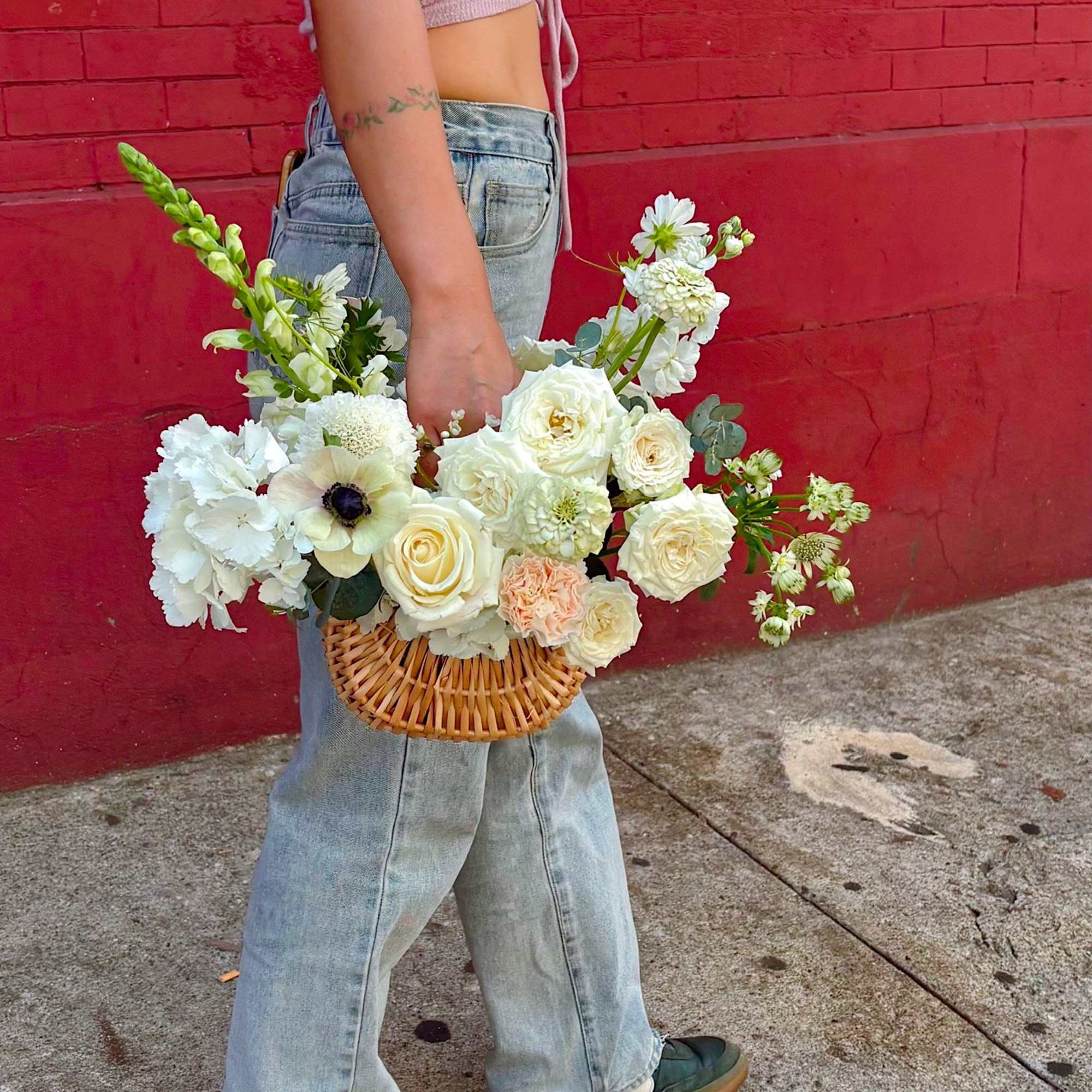 A fresh, garden-style flower basket filled with creamy white roses, seasonal blooms