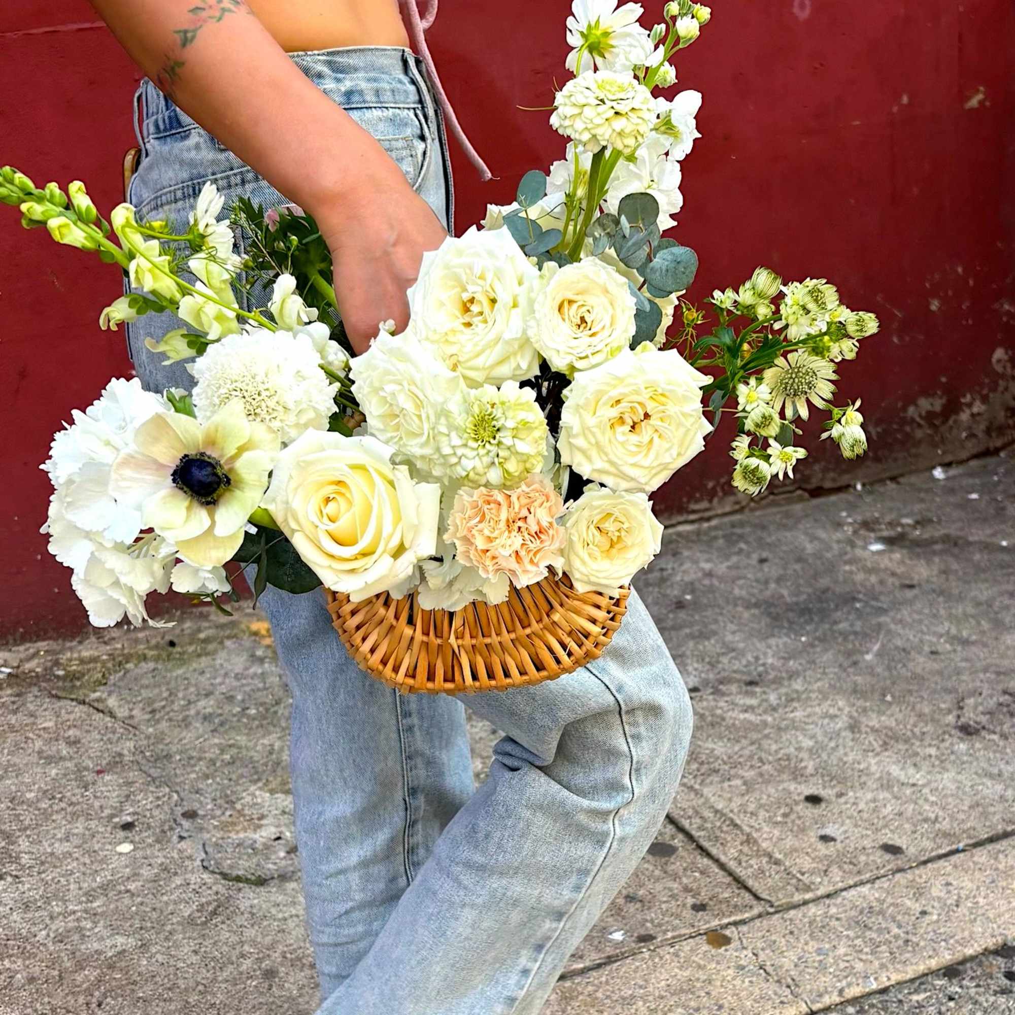A fresh, garden-style flower basket filled with creamy white roses, seasonal blooms