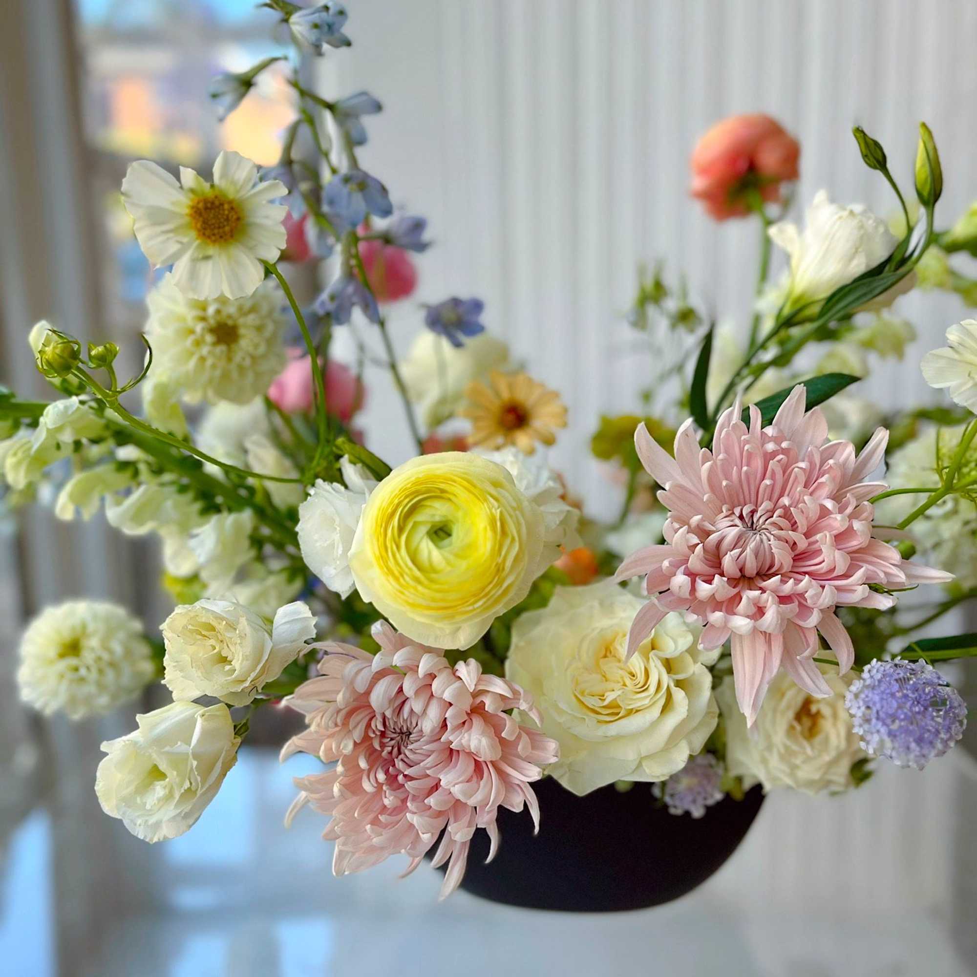 An airy, garden-inspired floral arrangement featuring blush chrysanthemums, creamy roses, ranunculus, and