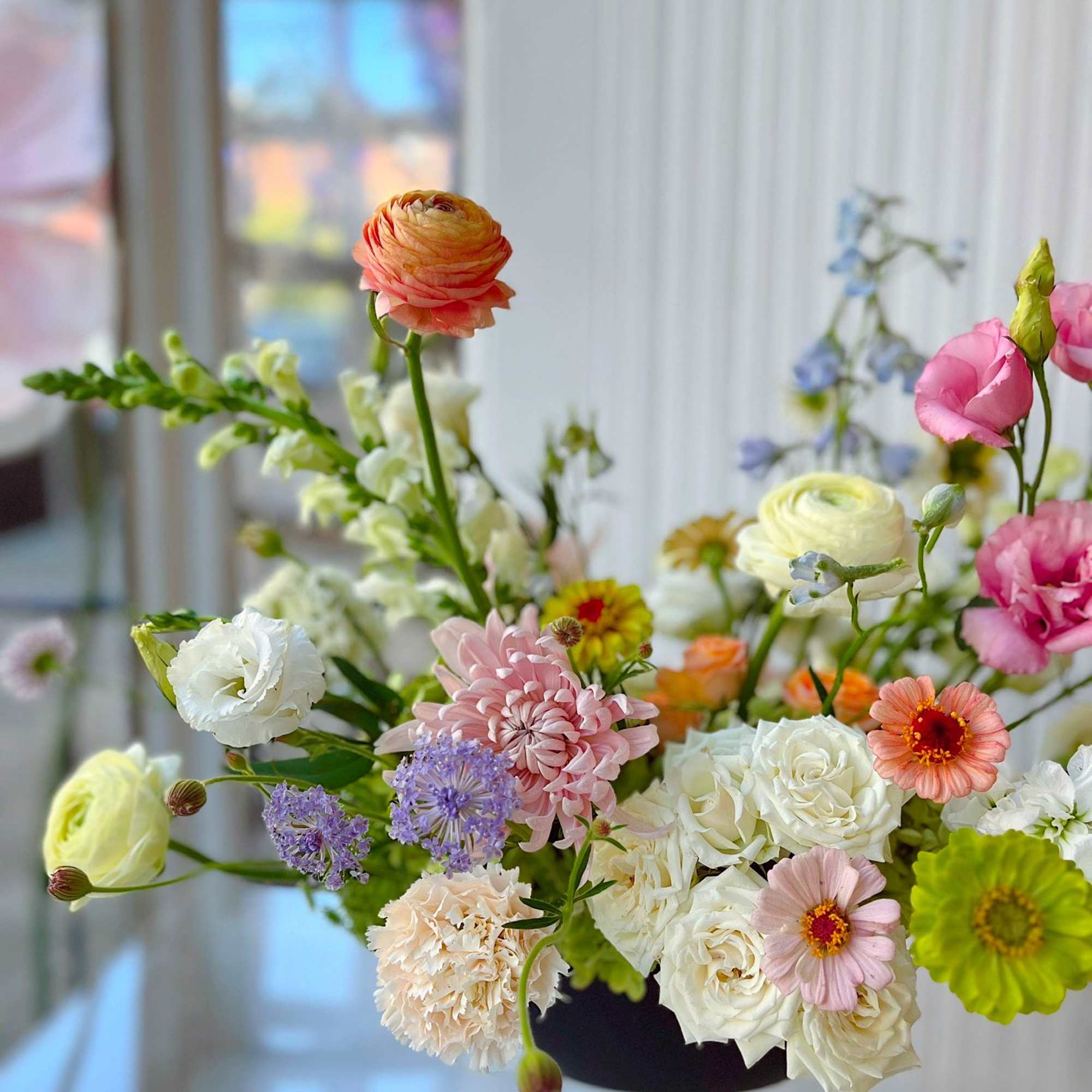 An airy, garden-inspired floral arrangement featuring blush chrysanthemums, creamy roses, ranunculus, and