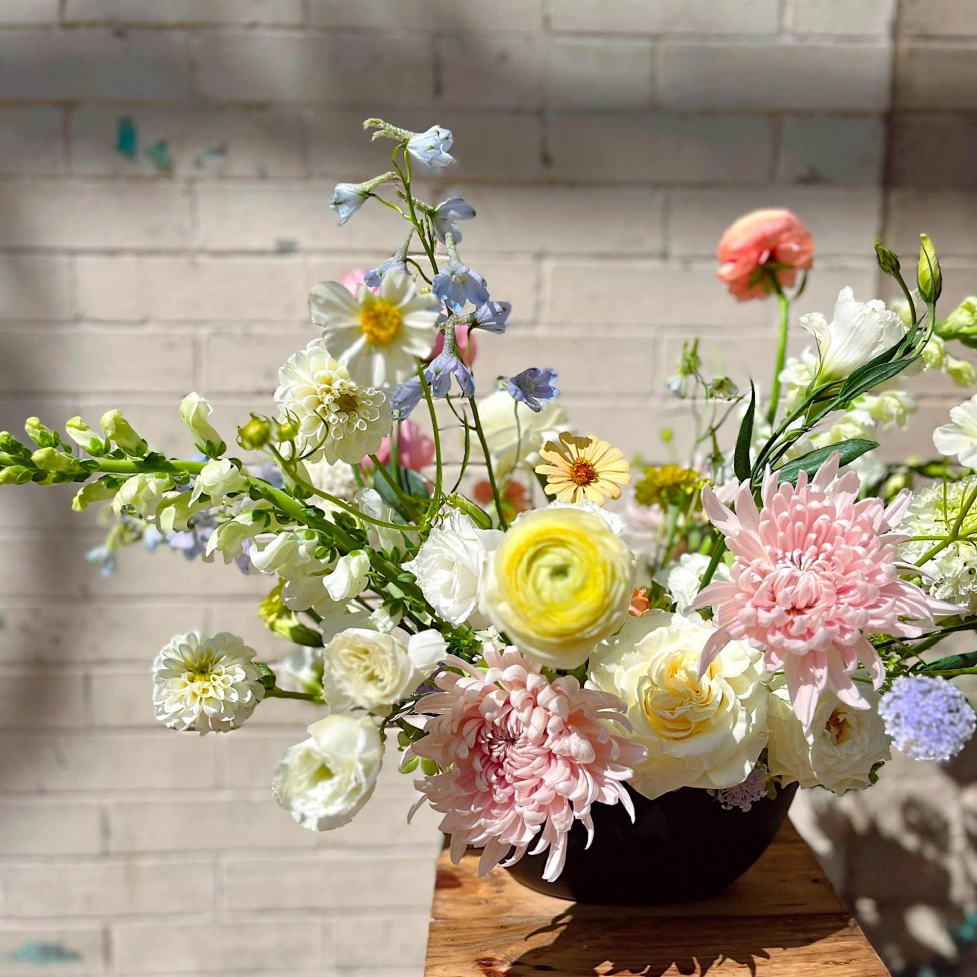 An airy, garden-inspired floral arrangement featuring blush chrysanthemums, creamy roses, ranunculus, and
