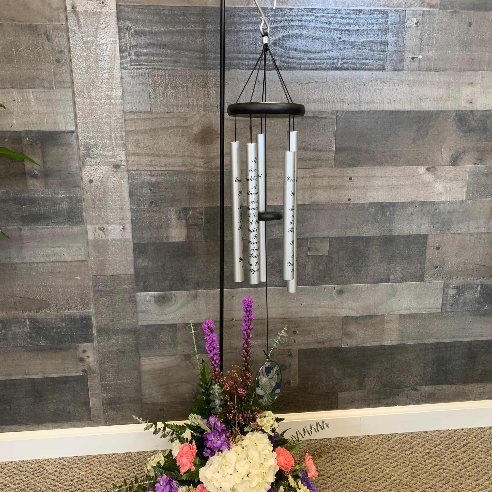 Hanging wind chime above a mixed floral arrangement in a floor stand