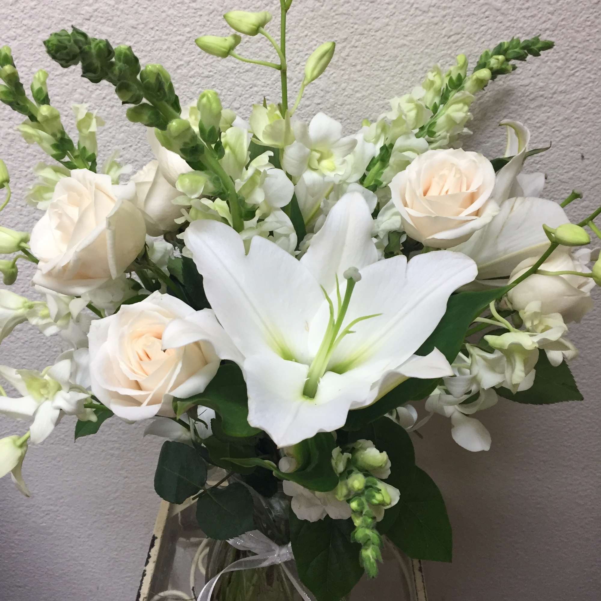 White lilies and cream roses arranged in a glass vase