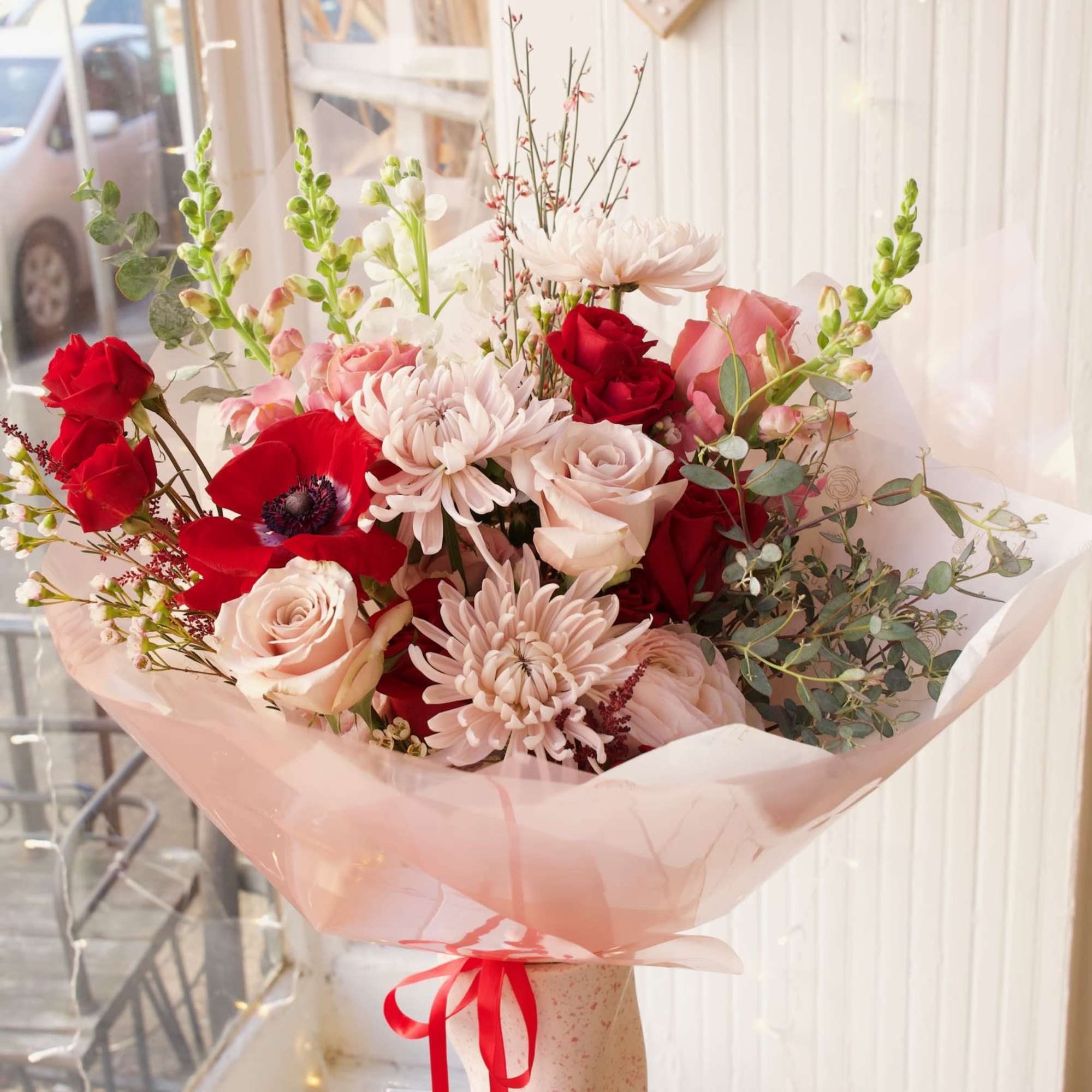 Bouquet of red and blush roses with pale pink blooms in pink wrap