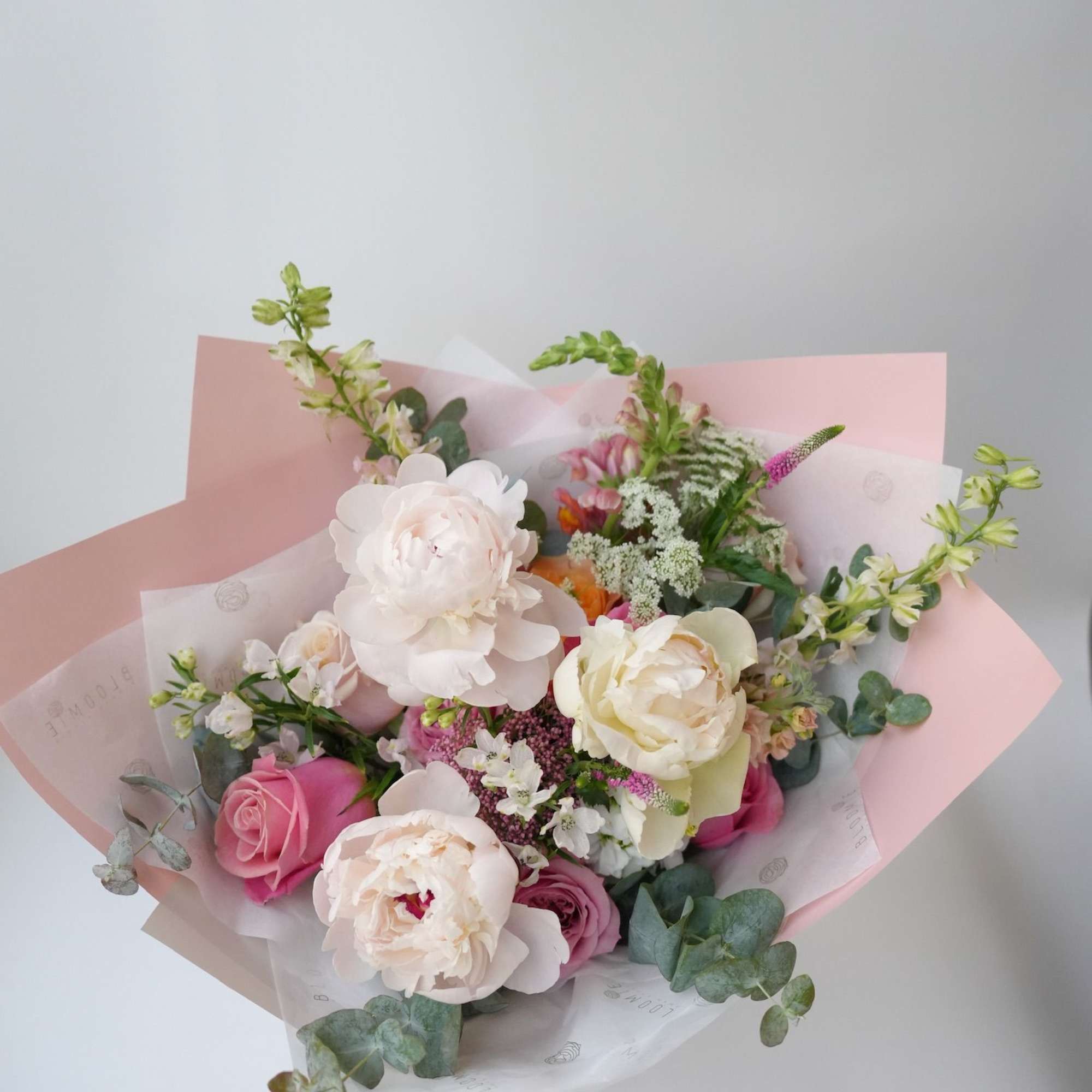 Bouquet of pink and white flowers wrapped in pastel paper