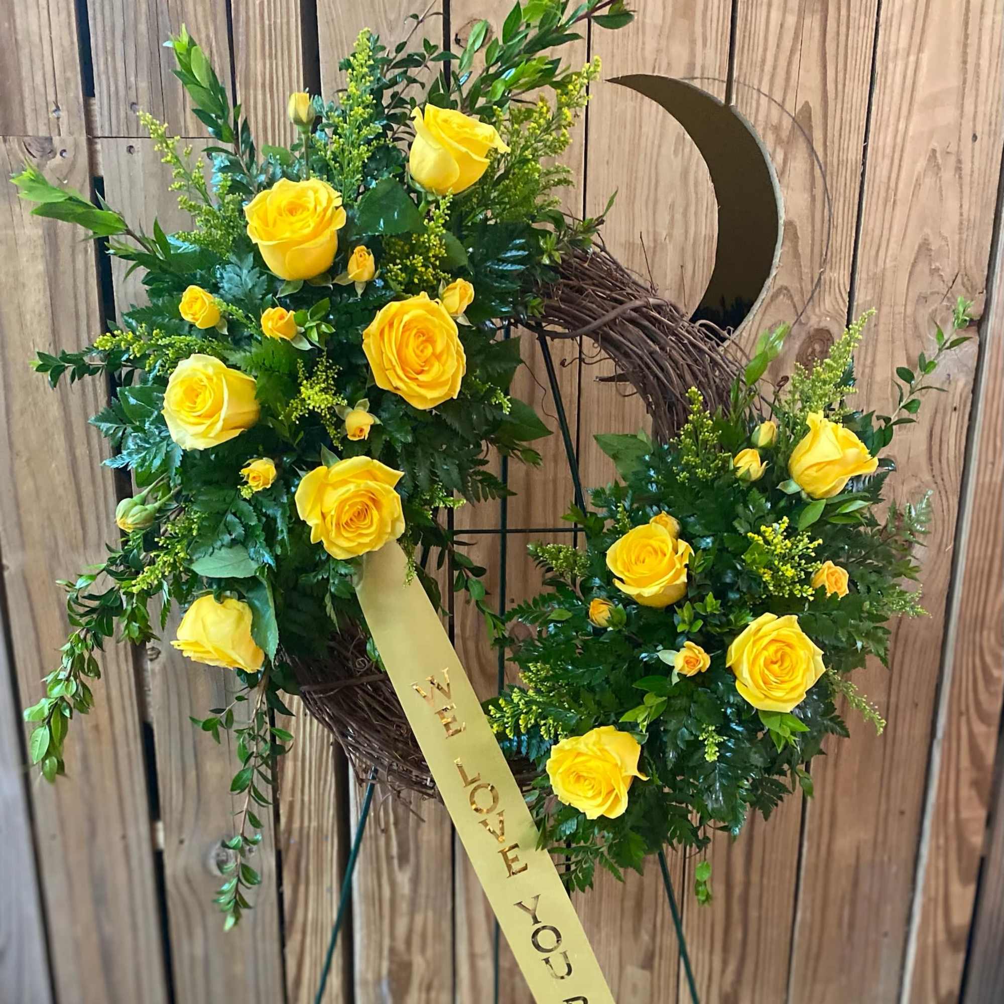 Yellow rose wreath with a ribbon on a stand