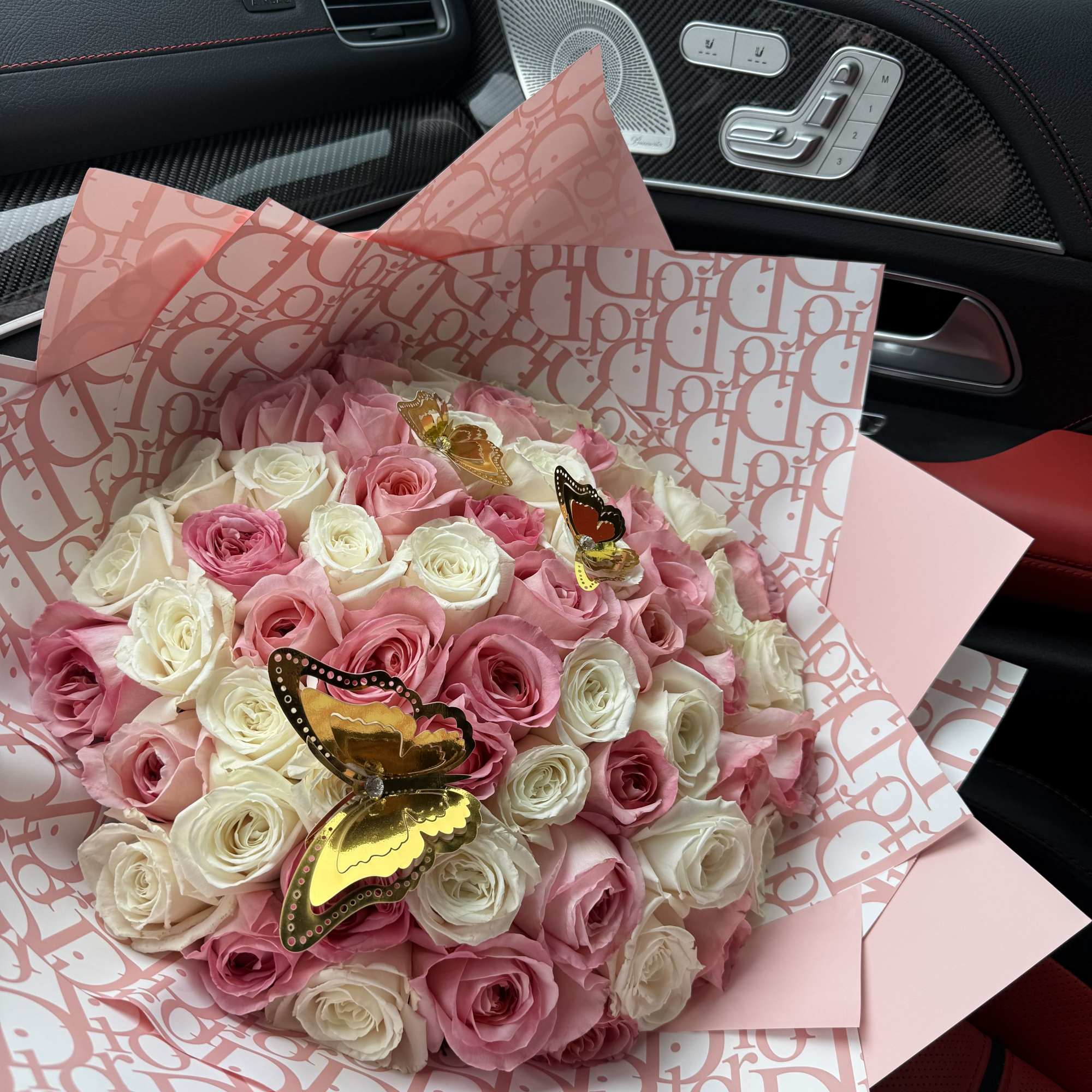 Pink and white rose bouquet wrapped in patterned paper with butterfly picks