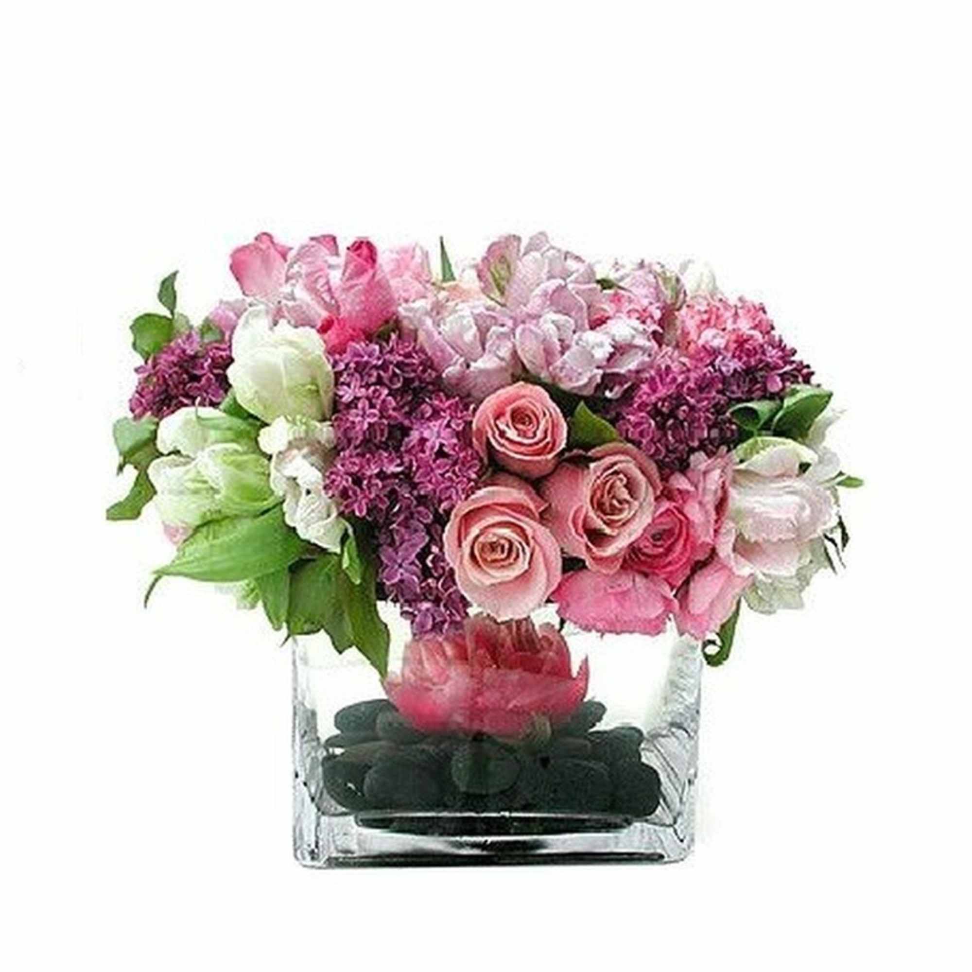 Low pink and purple flower arrangement in a clear square vase with black stones