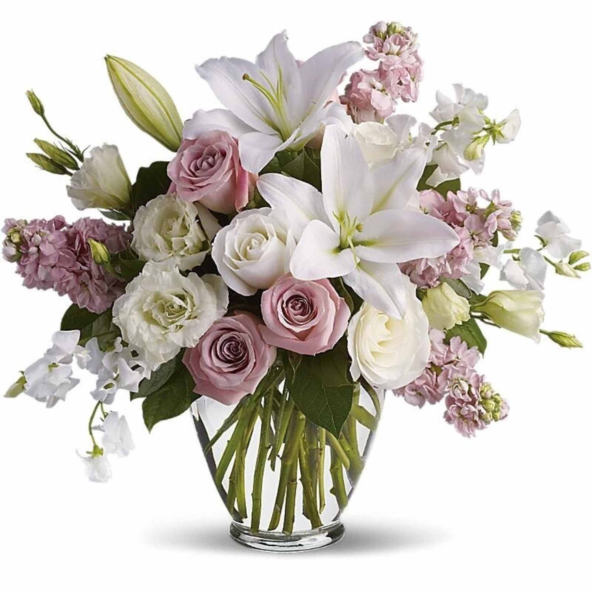 Arrangement of white lilies and soft pink and white roses in a clear glass vase