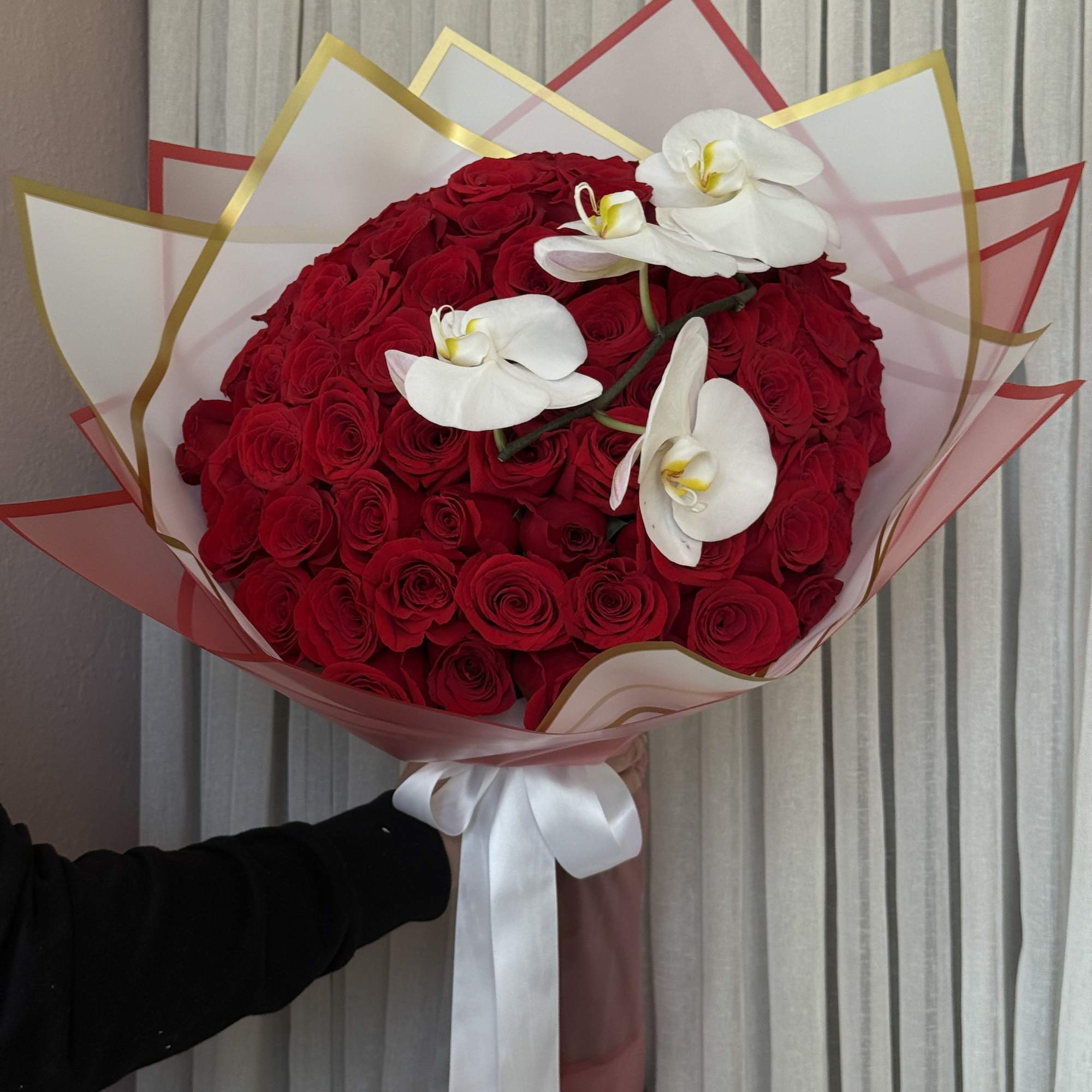 Large bouquet of red roses with white orchids and a white ribbon