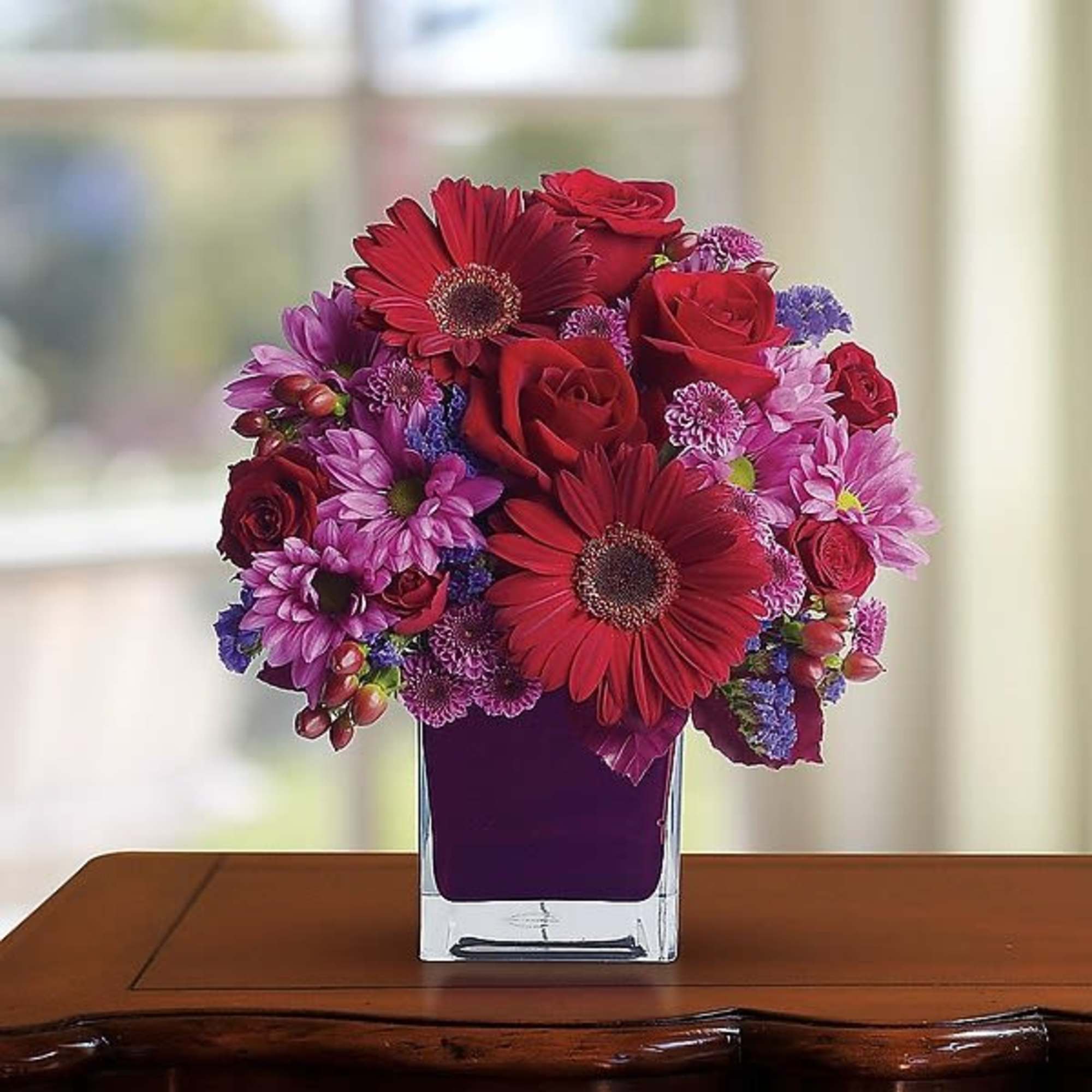 Rich jewel-toned flowers are arranged in a chic cube vase for a