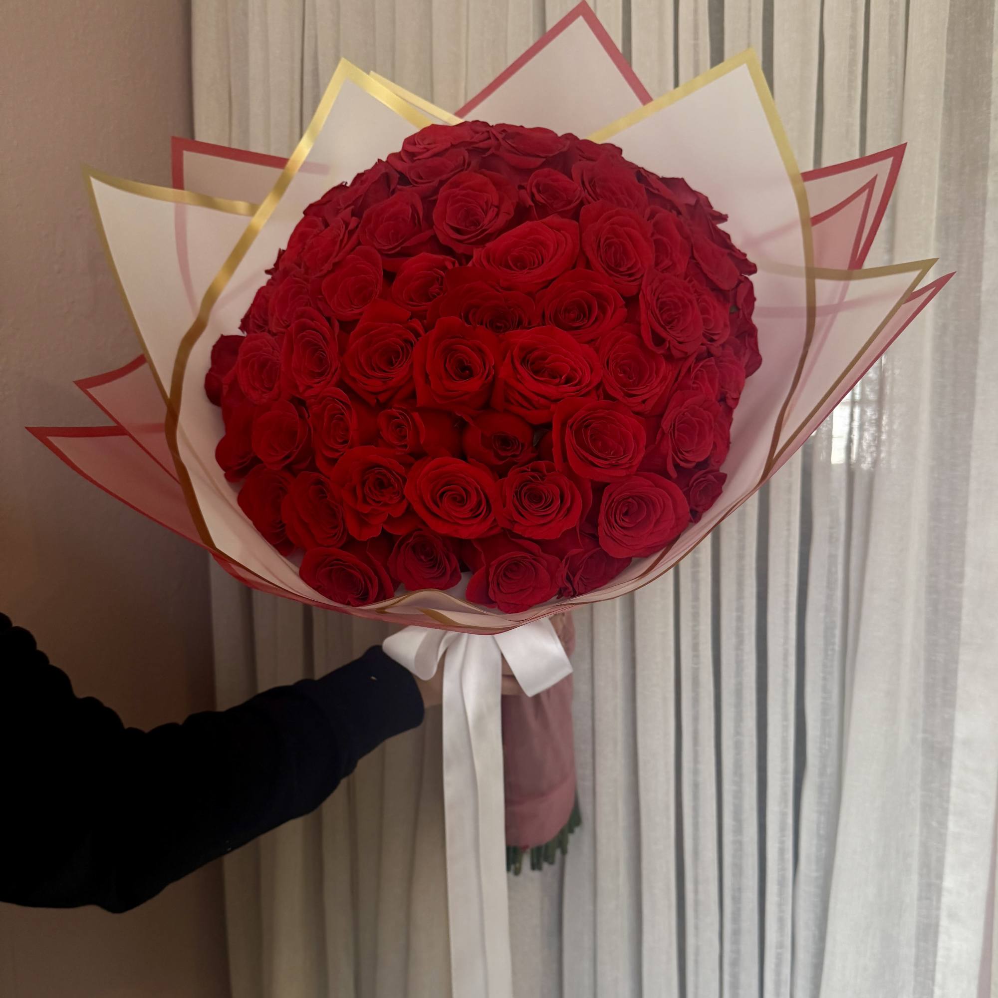 Large bouquet of red roses wrapped in white and gold paper