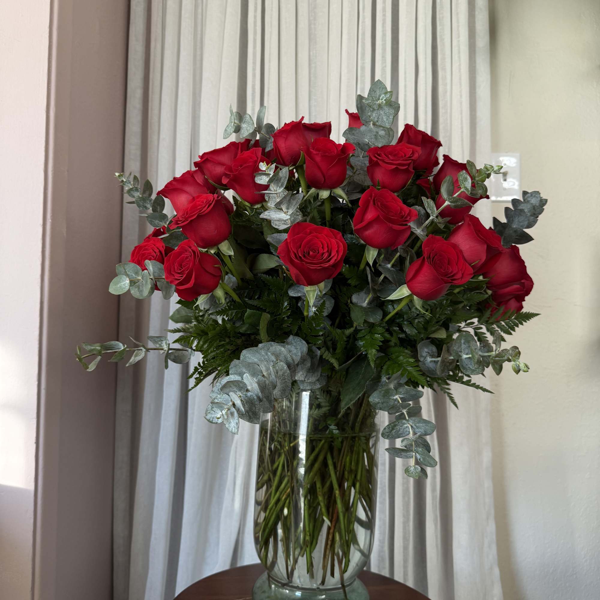 Bouquet of red roses in a glass vase with eucalyptus