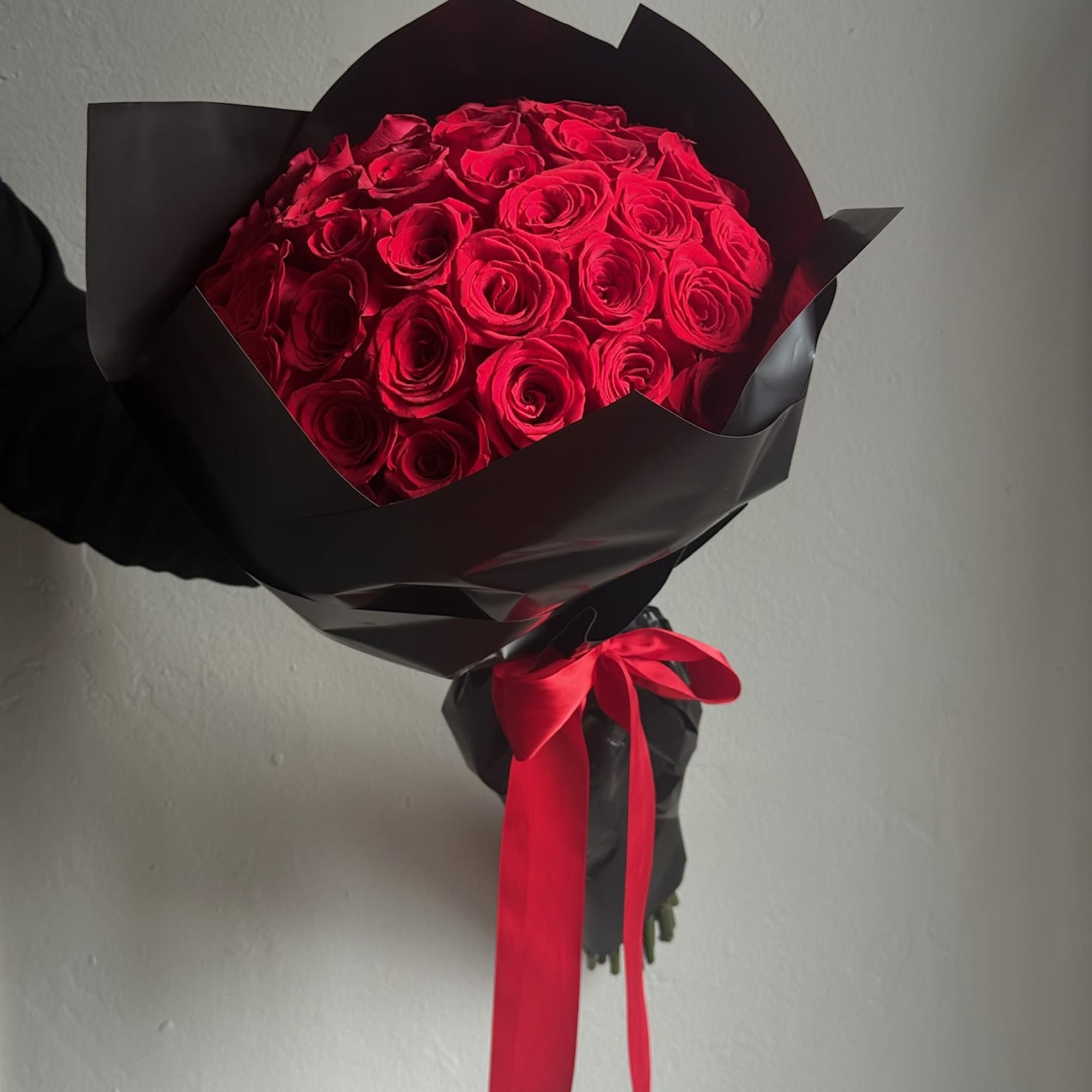 Bouquet of red roses wrapped in black paper with a red ribbon