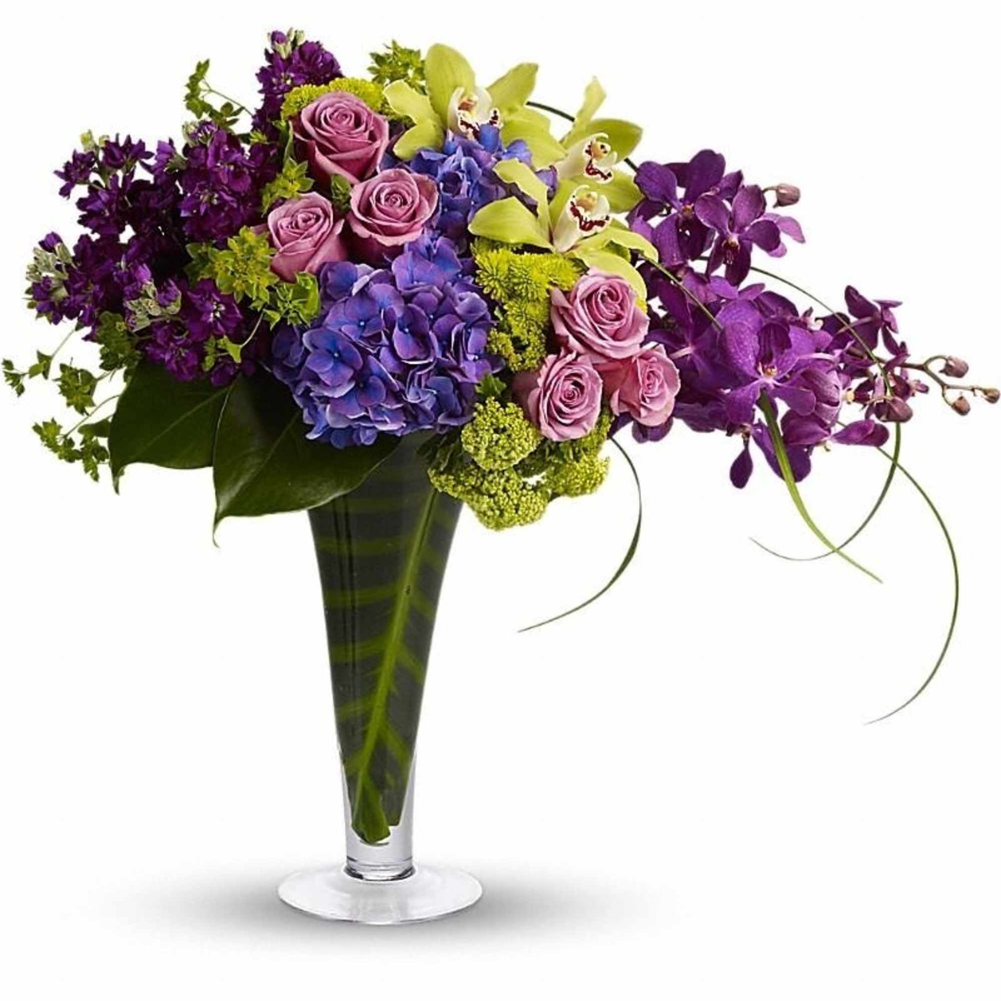 Tall modern arrangement of purple orchids, blue hydrangea, green orchids and lavender roses in a clear vase