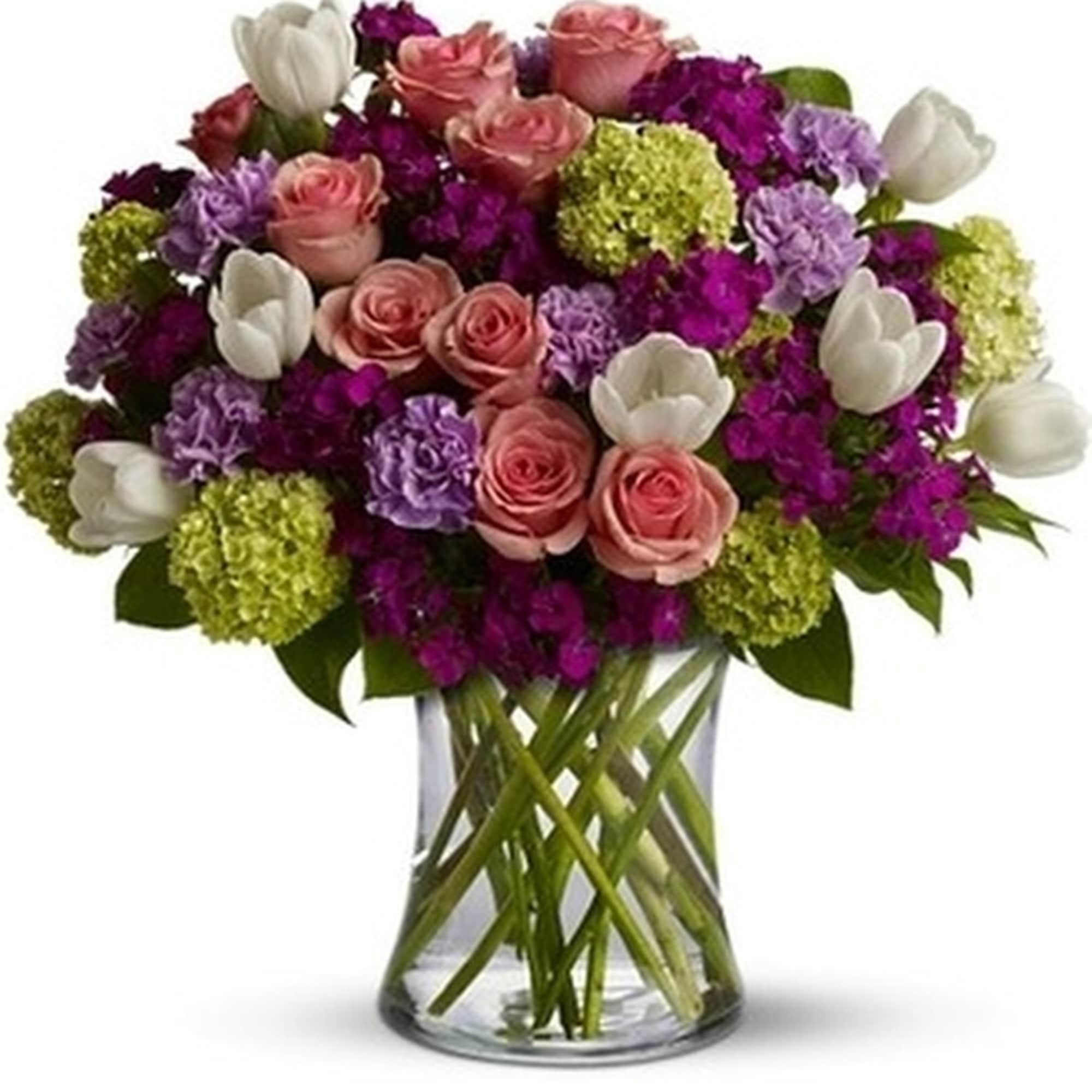 Mixed bouquet of pink roses, white tulips and purple flowers in a clear glass vase