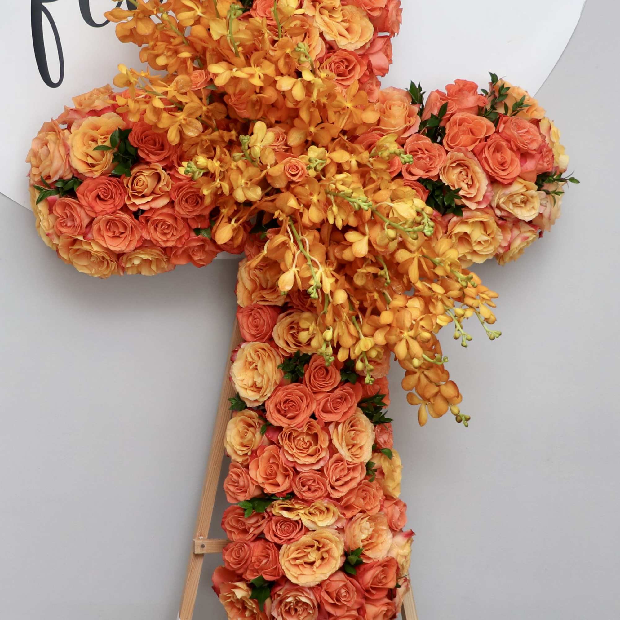 This cross is covered in orange roses and orchids.

We include easel, printed
