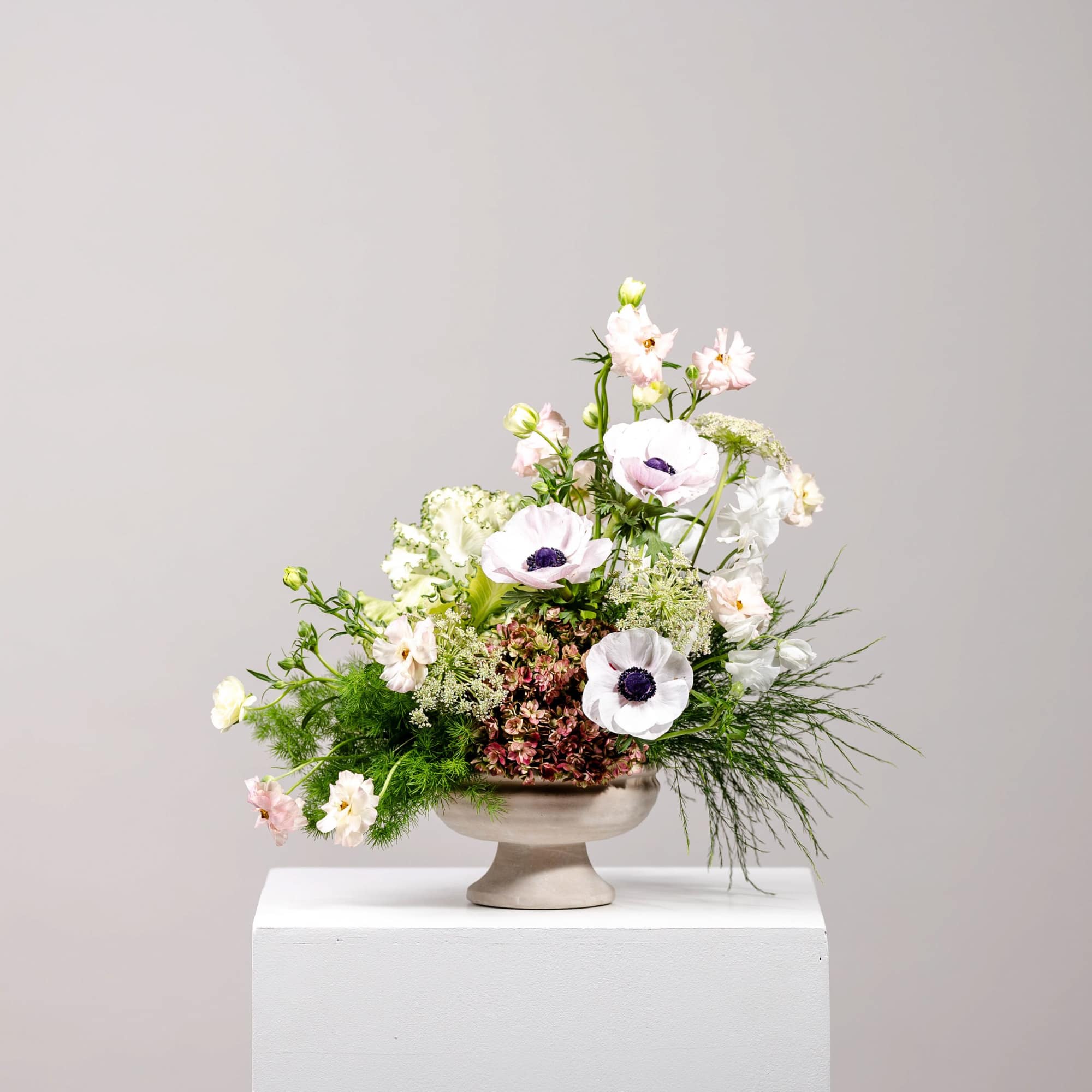 Pastel floral arrangement in a pedestal vase with white and pink blooms
