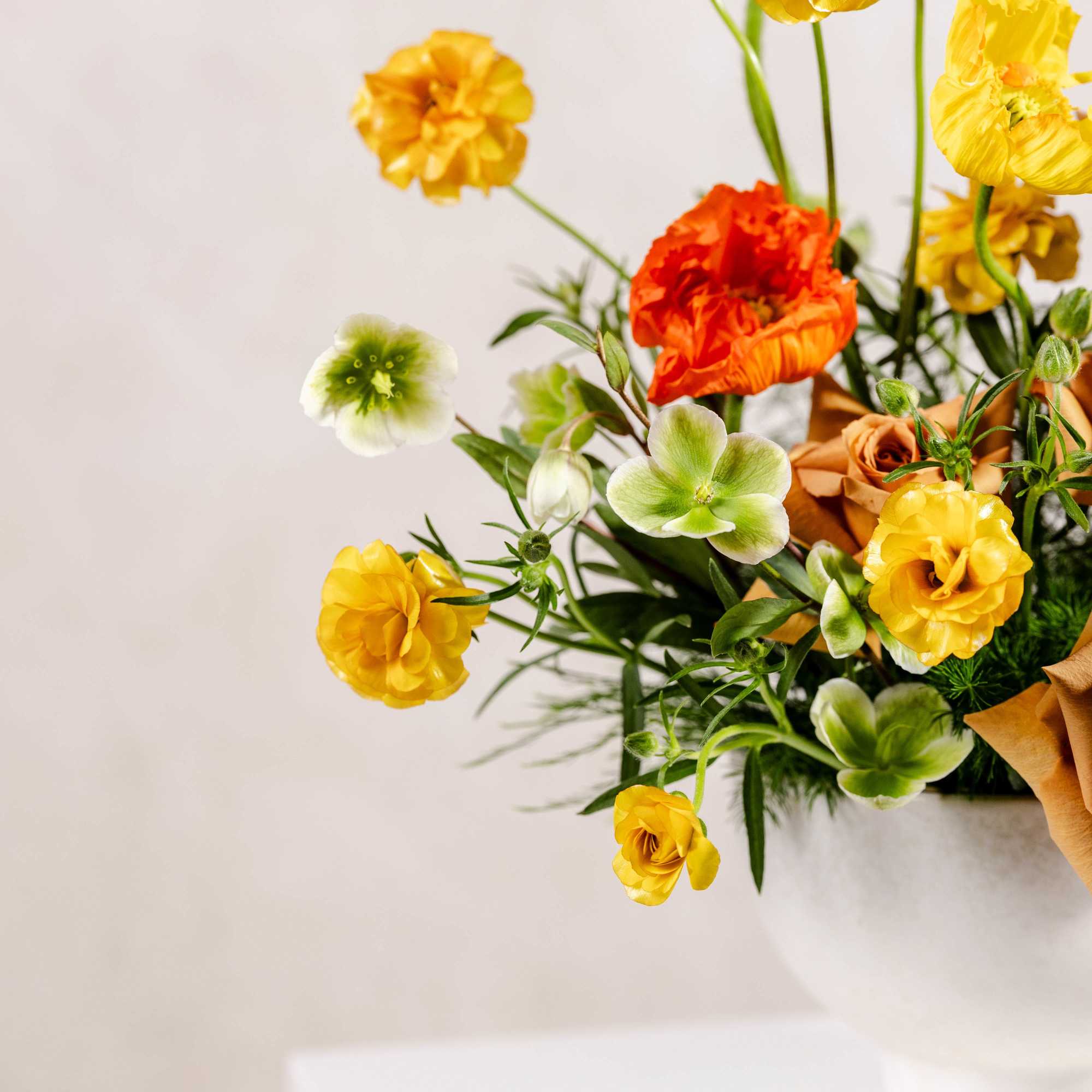 Arrangement of yellow, orange, and tan flowers in a white vase