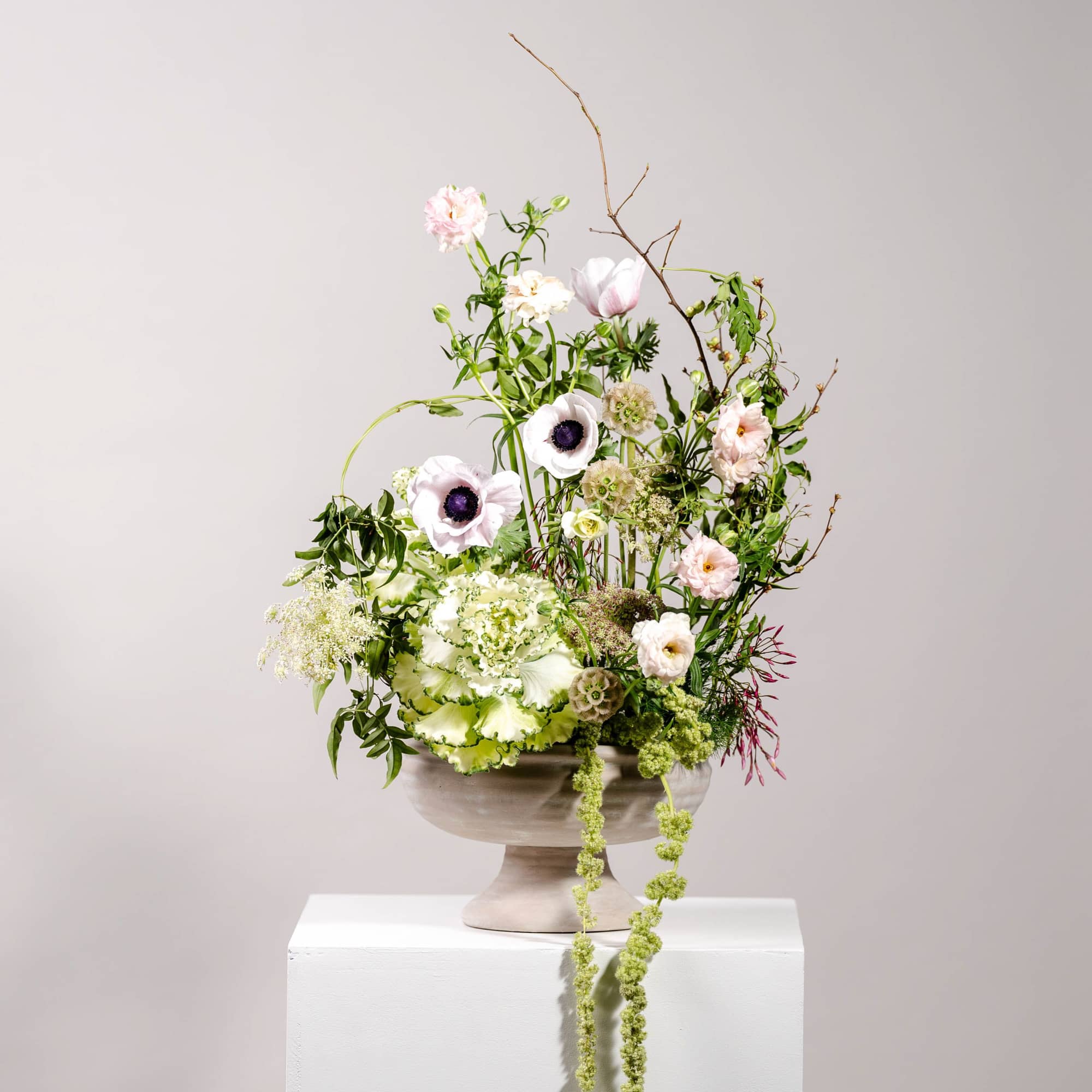 Tall floral arrangement in a pedestal bowl with pale pink and white blooms
