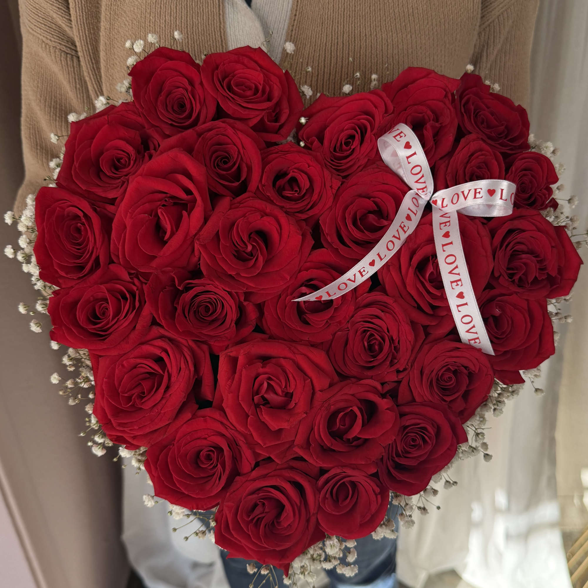 Heart-shaped bouquet of red roses with a love ribbon