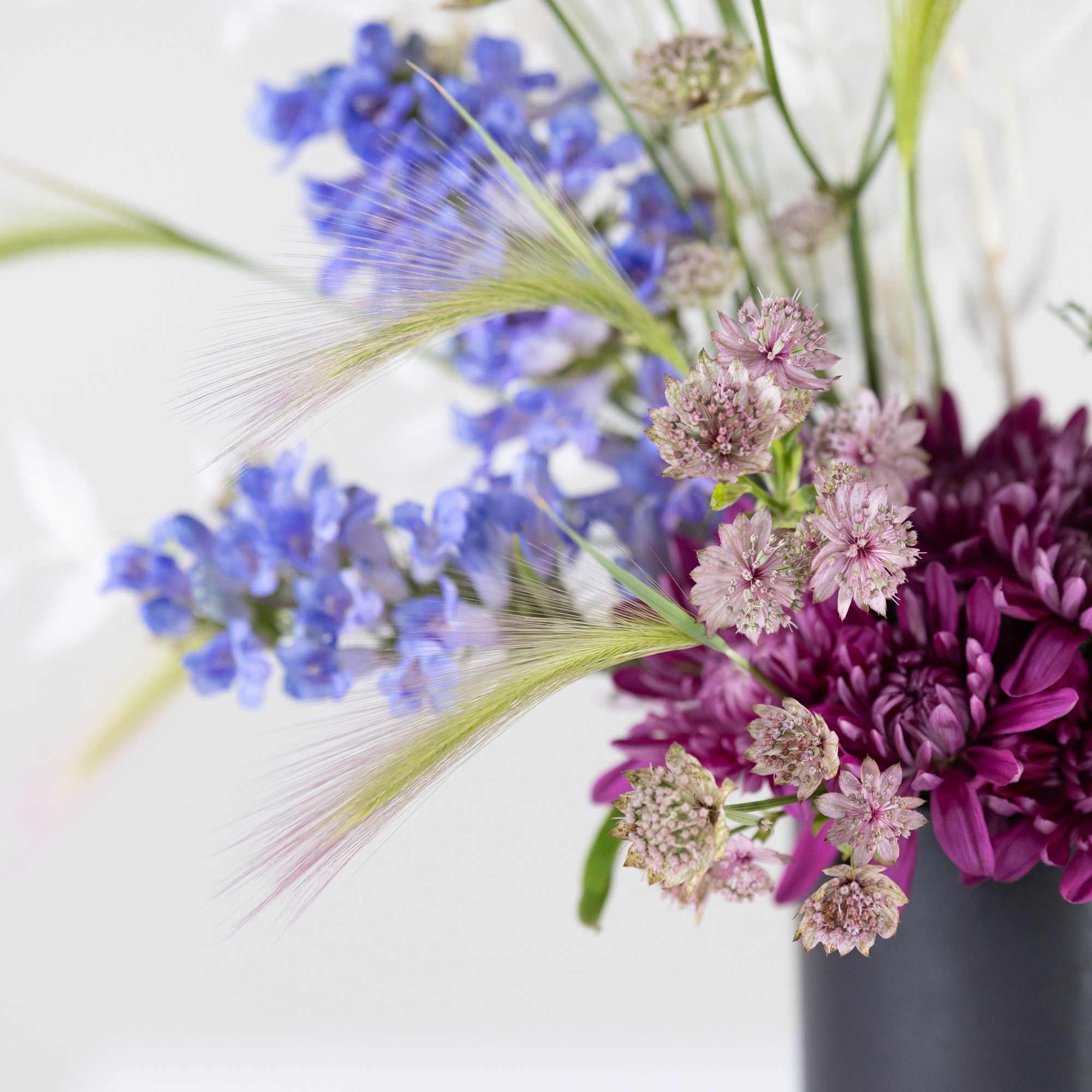 Purple and blue flowers arranged in a dark vase