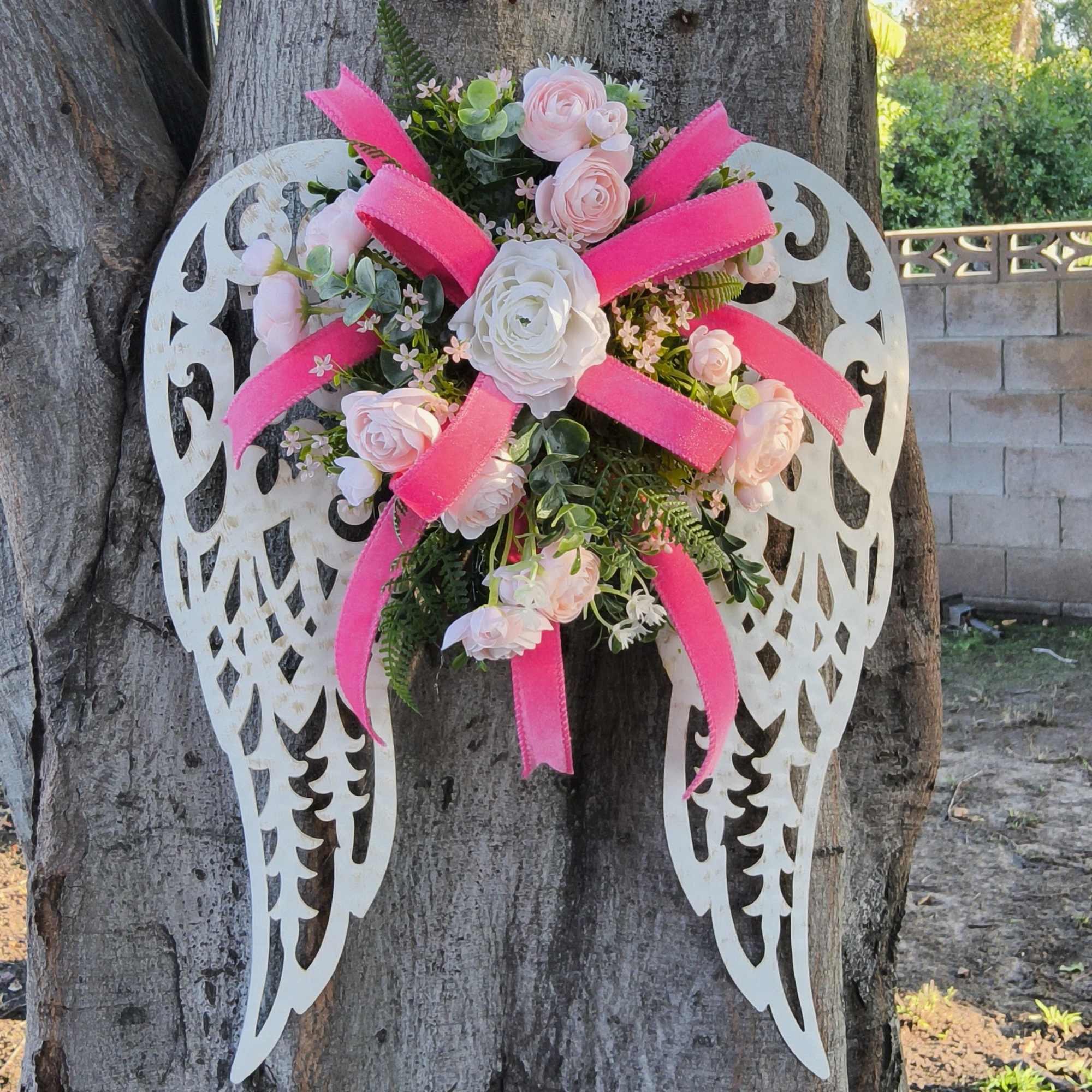 Floral angel wings with pink and white roses on a tree trunk