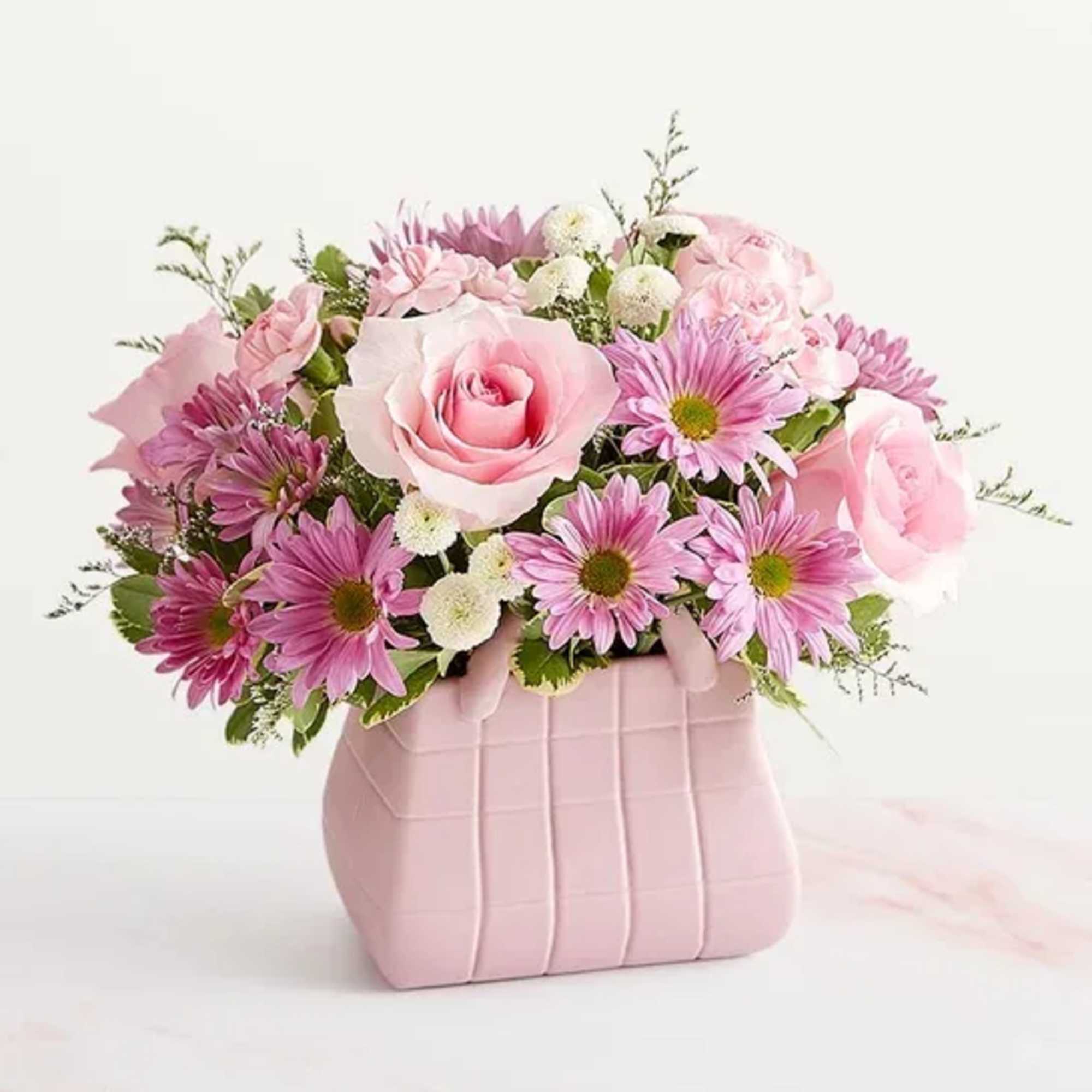 Pink roses and purple daisies arranged in a pink vase