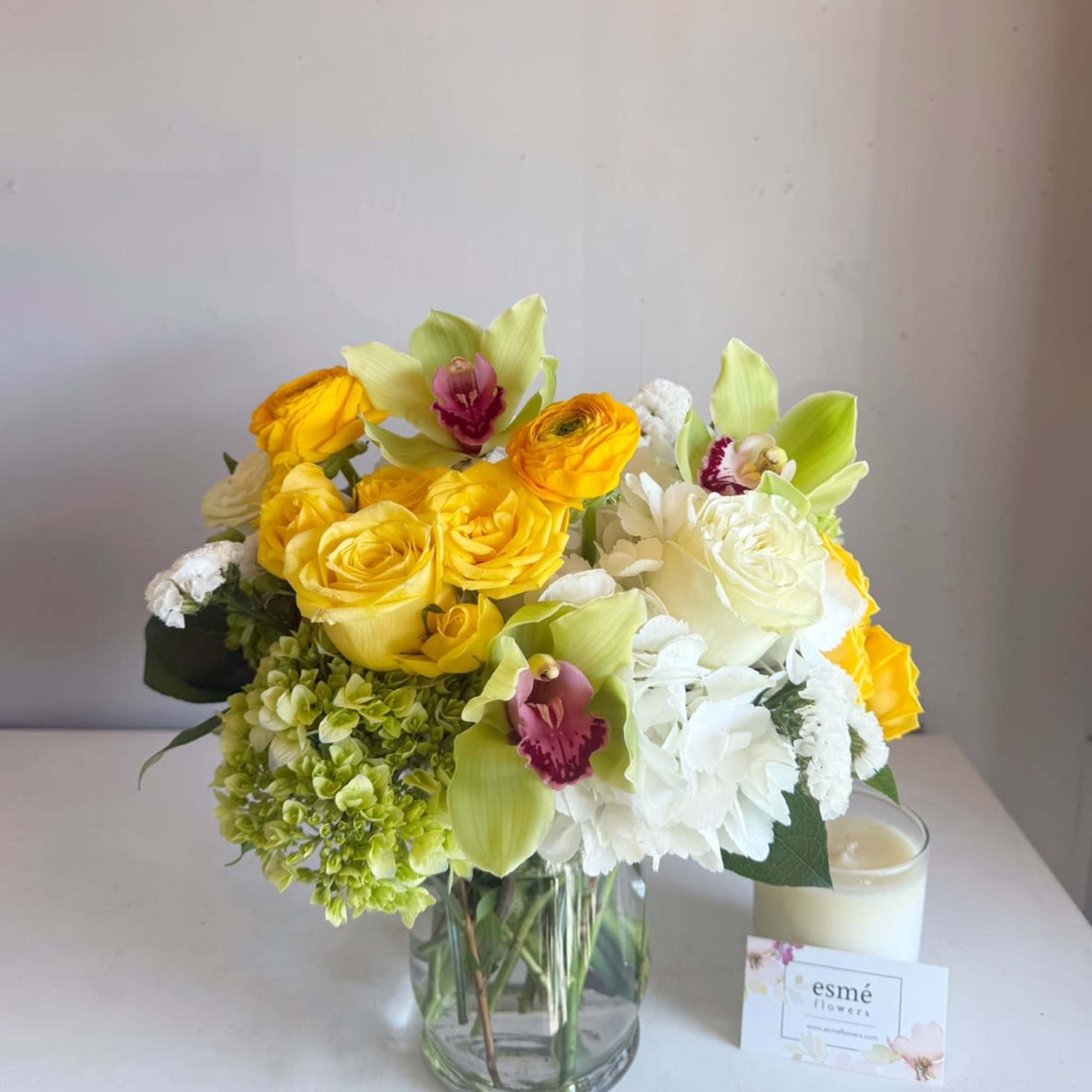Yellow roses and white orchids in a clear glass vase