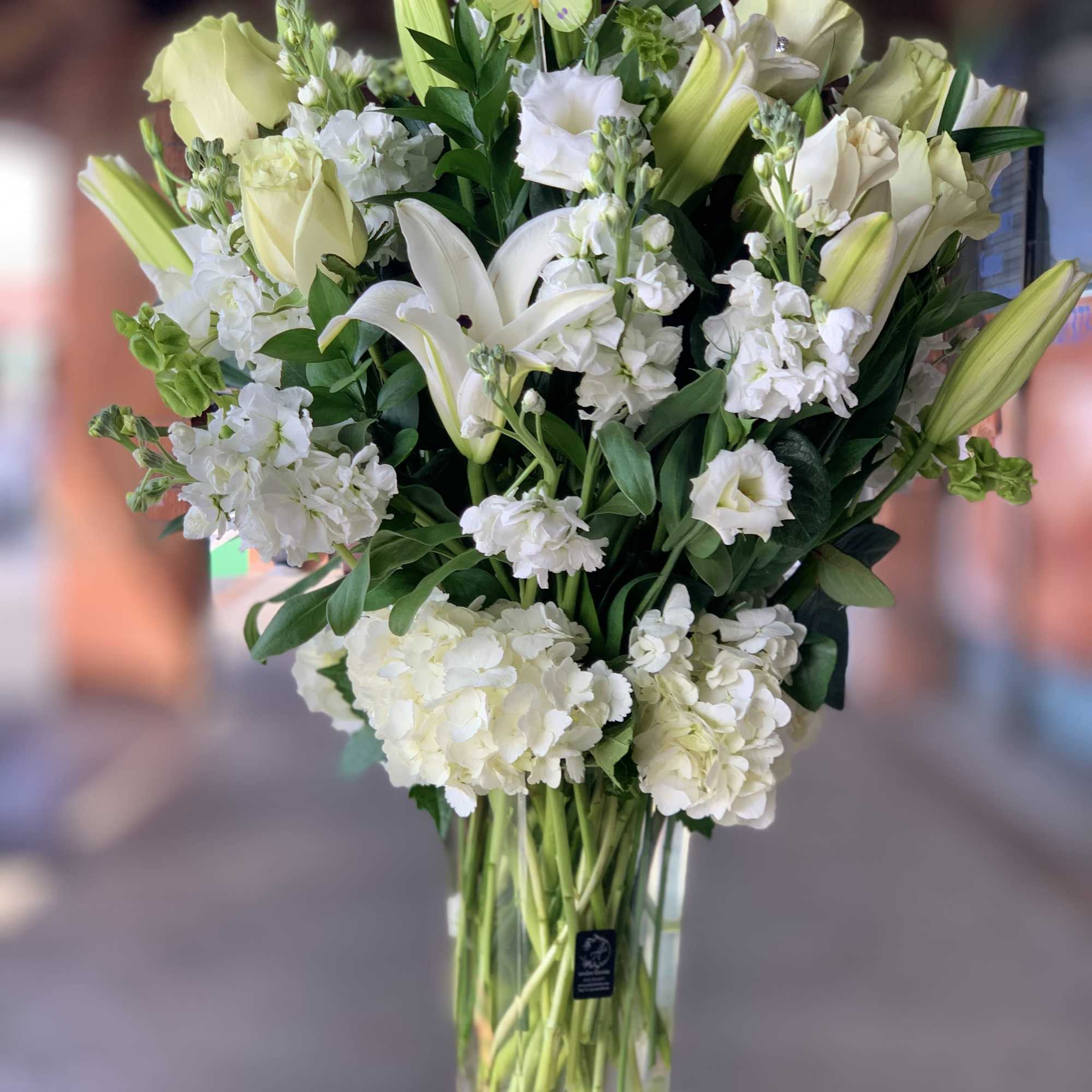 White lilies and pale roses in a tall glass vase