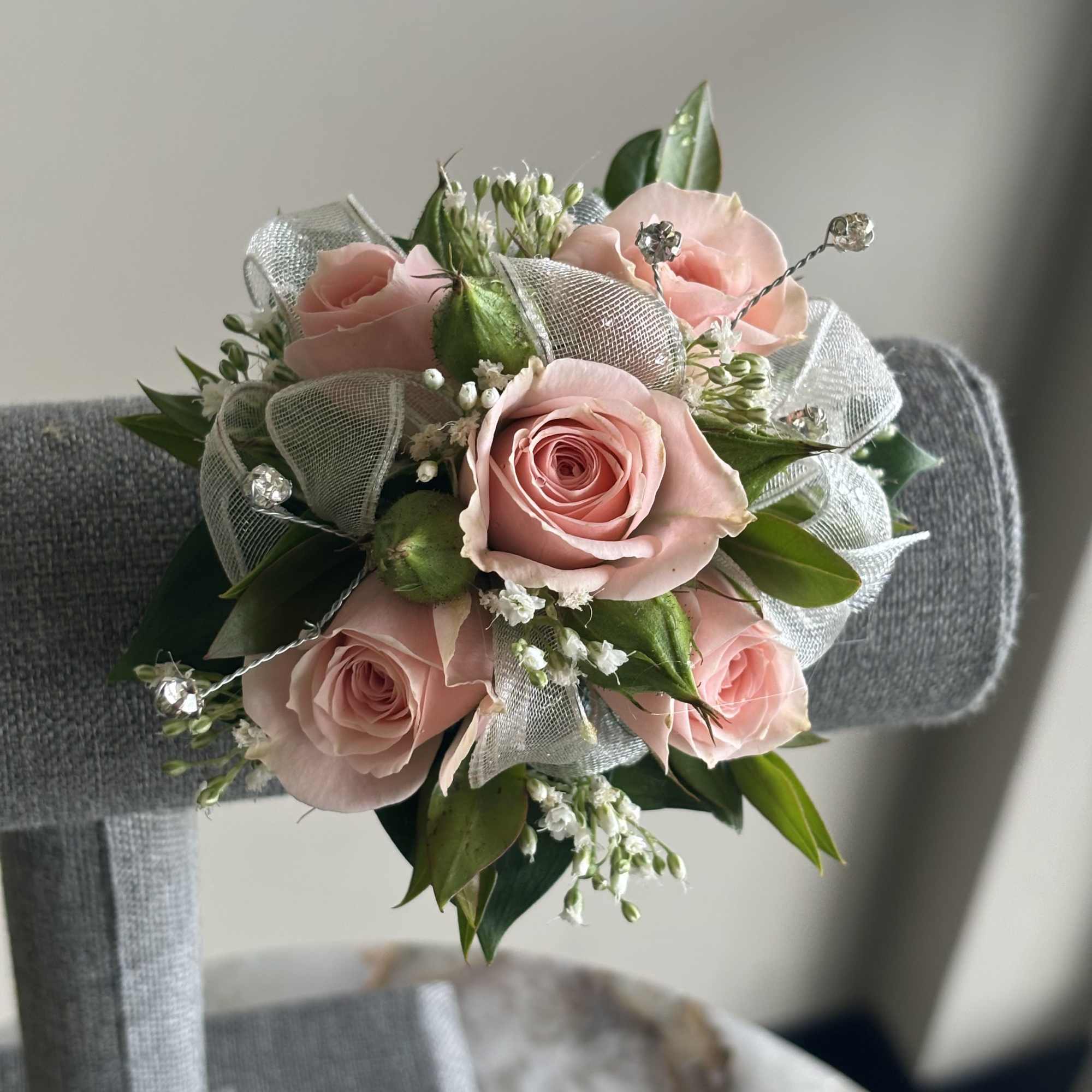 Small round bouquet of soft pink roses with white filler flowers and silver ribbon accents