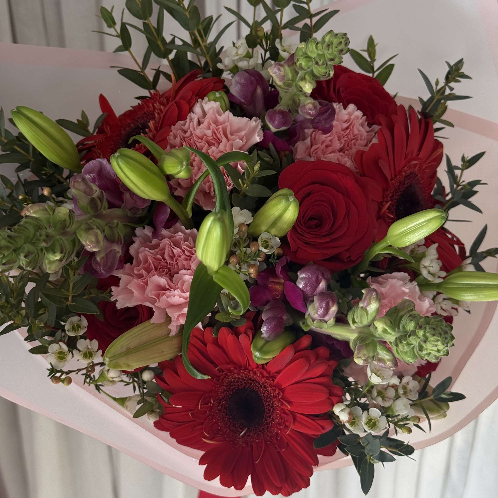 Bouquet of red gerberas, roses, pink carnations, and lily buds