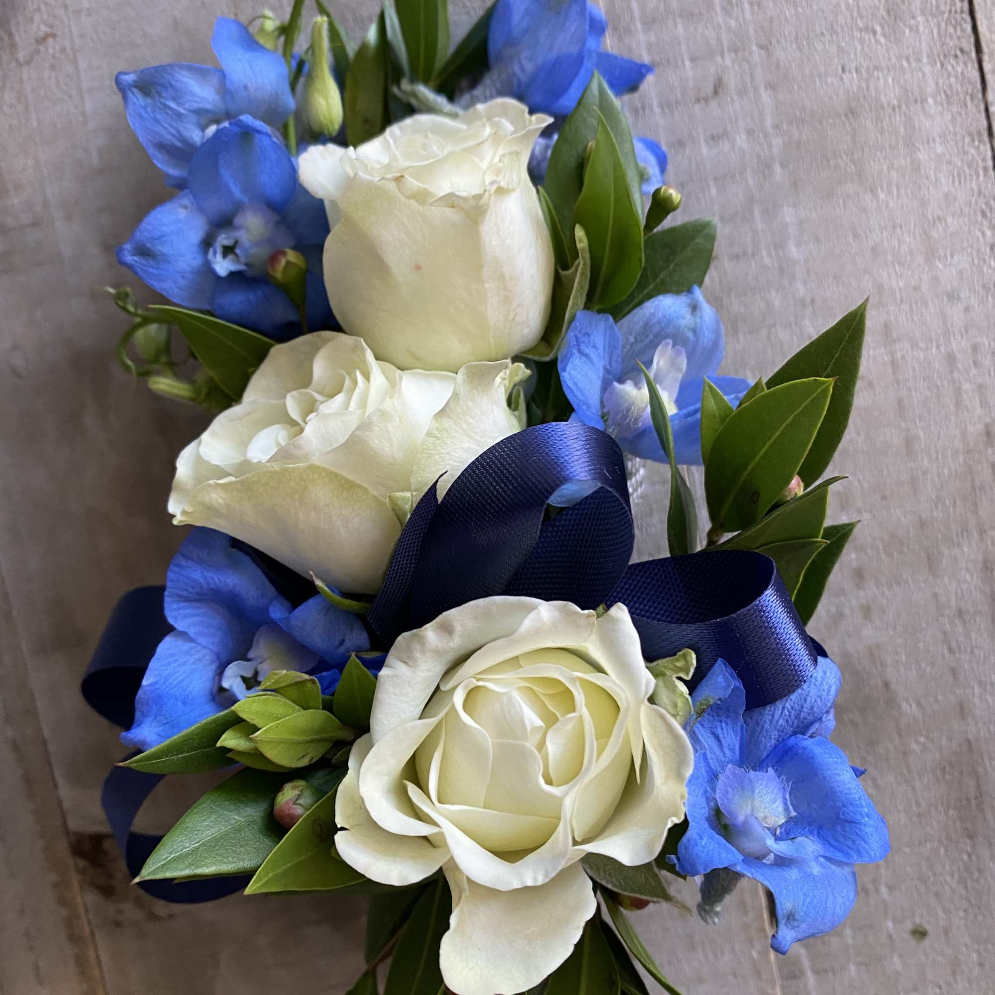White roses and blue flowers tied with a navy ribbon