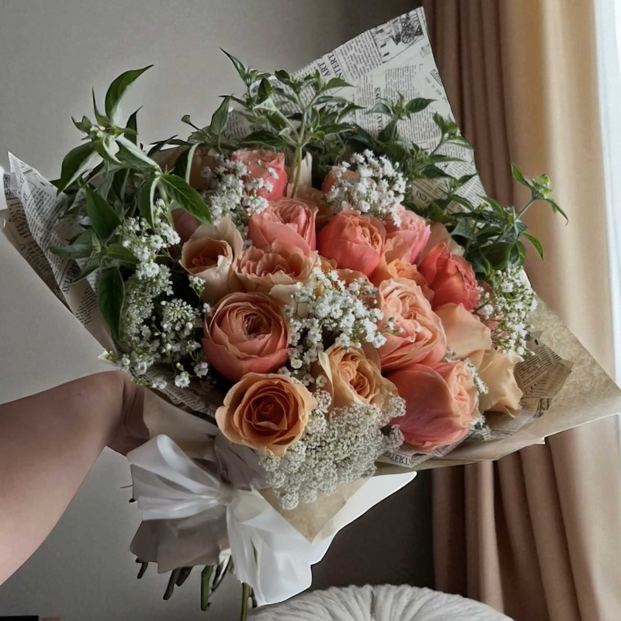 Peach and coral rose bouquet with white filler flowers and greenery