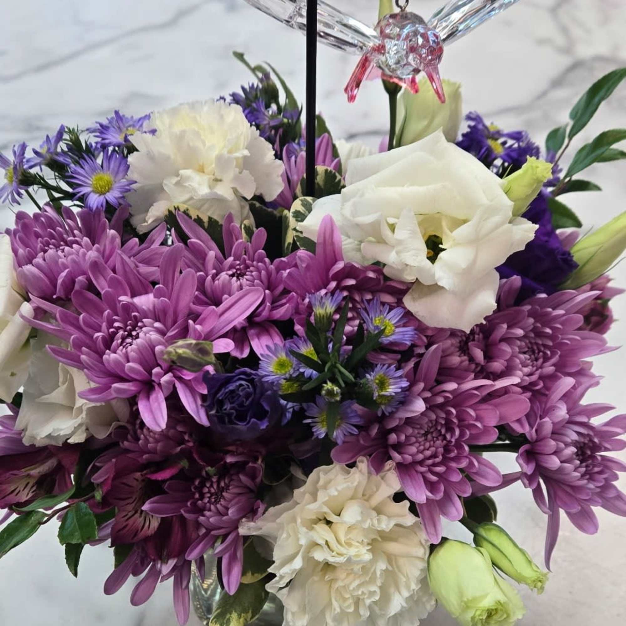 A compact cluster of soft purples, pinks, and creams-this flower arrangement "Whispers