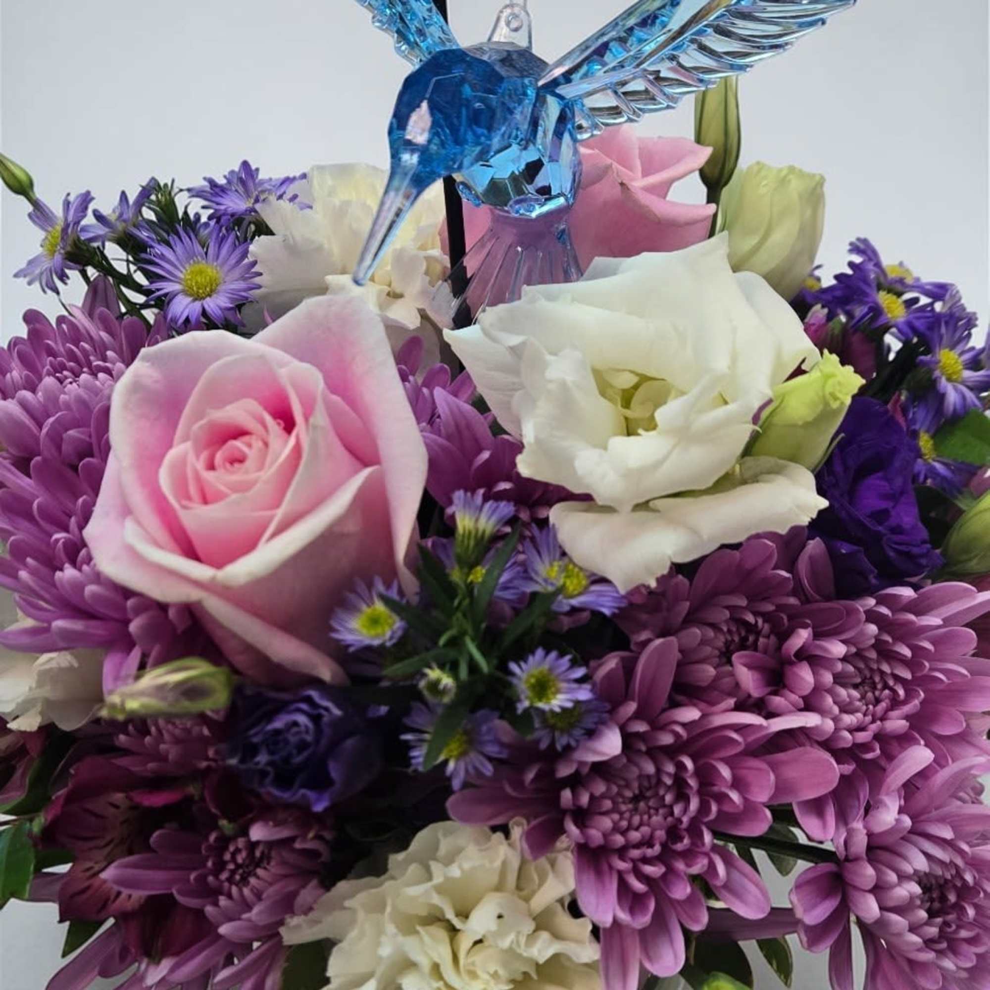 A compact cluster of soft purples, pinks, and creams-this flower arrangement "Whispers