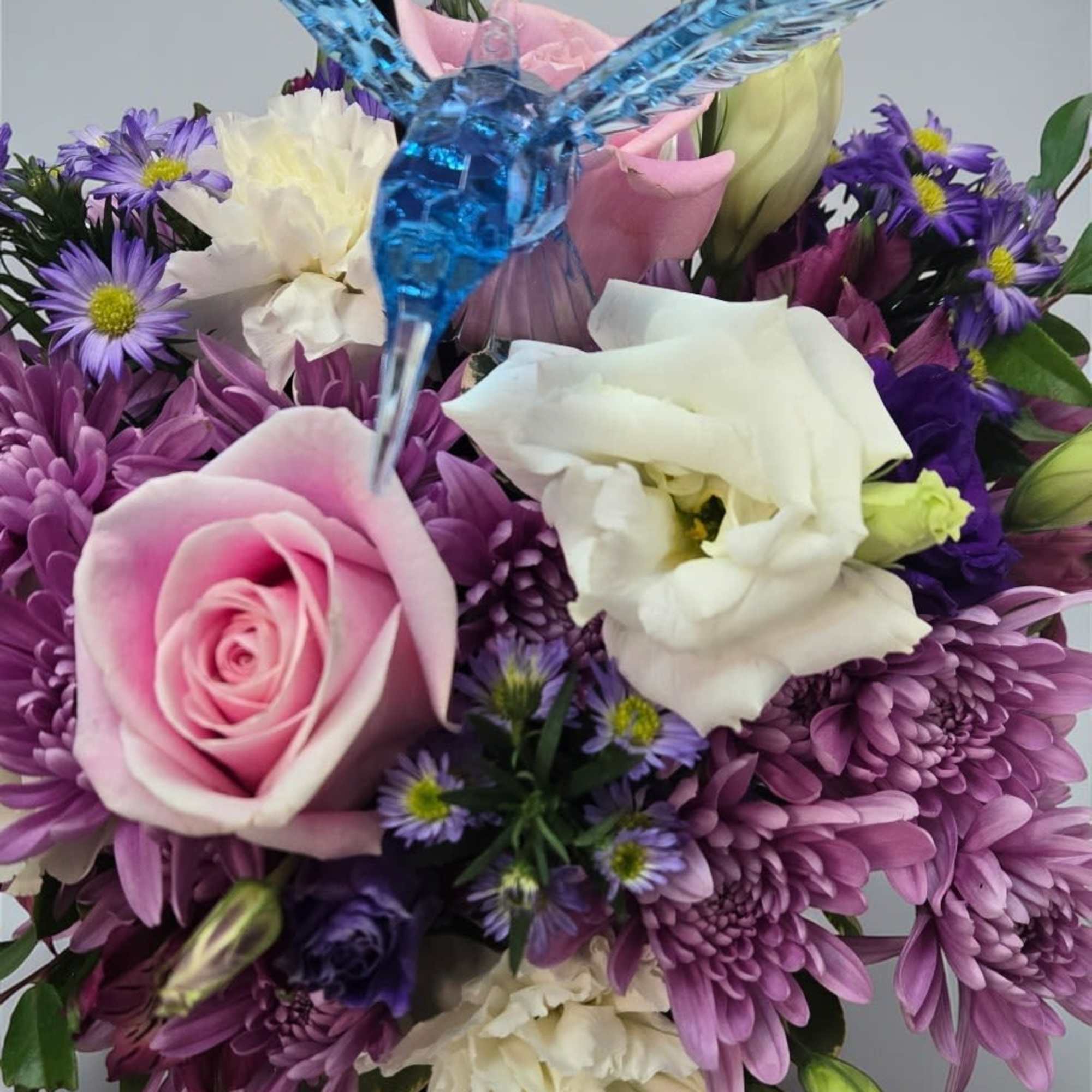 A compact cluster of soft purples, pinks, and creams-this flower arrangement "Whispers