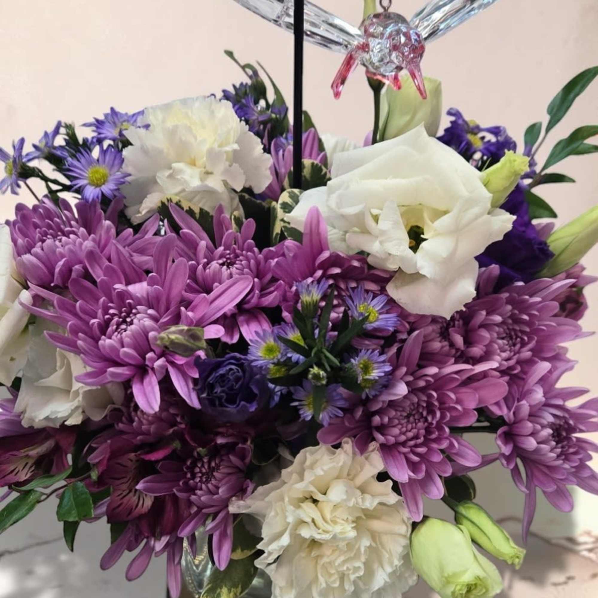 A compact cluster of soft purples, pinks, and creams-this flower arrangement "Whispers