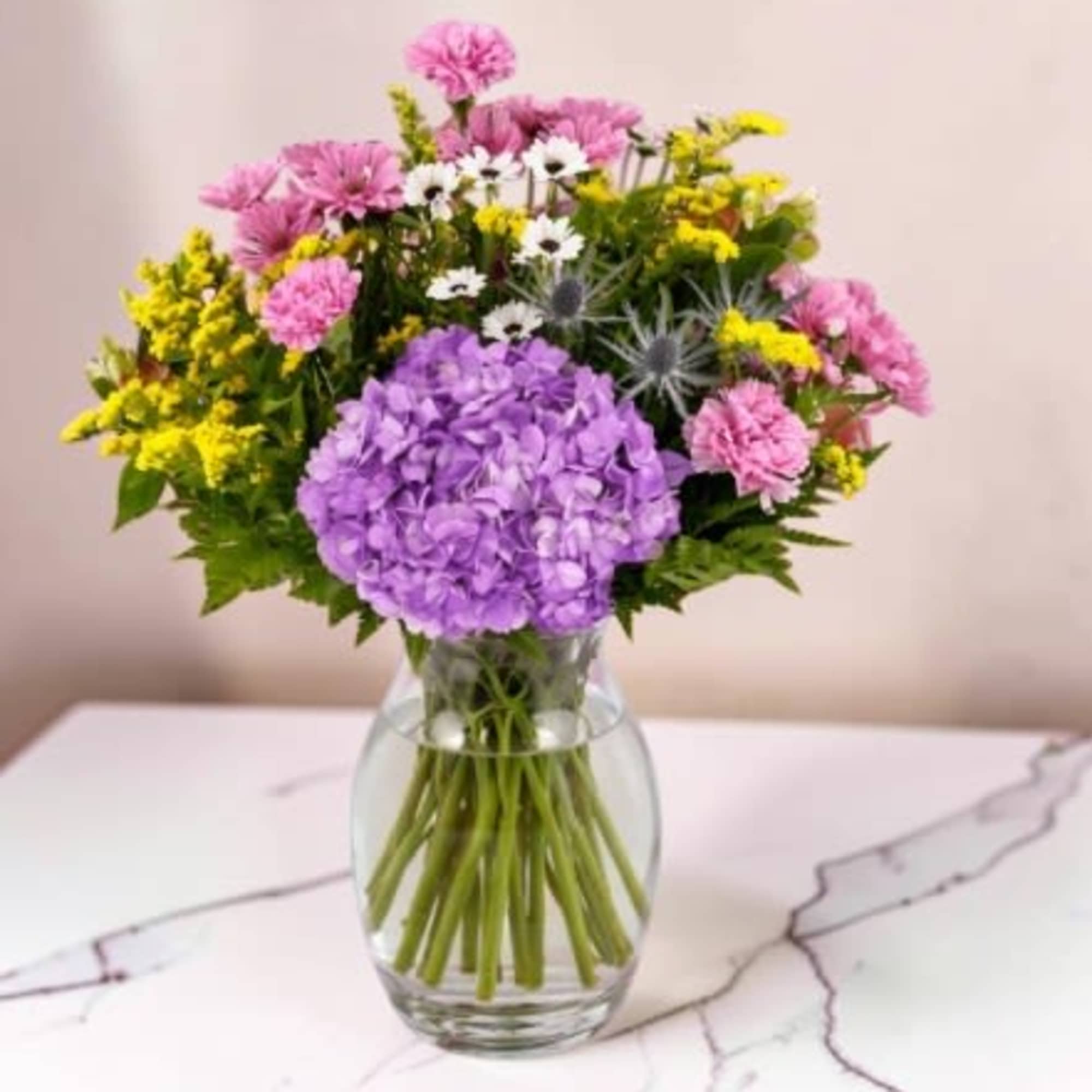  A colorful bouquet of flowers arranged in a textured purple glass