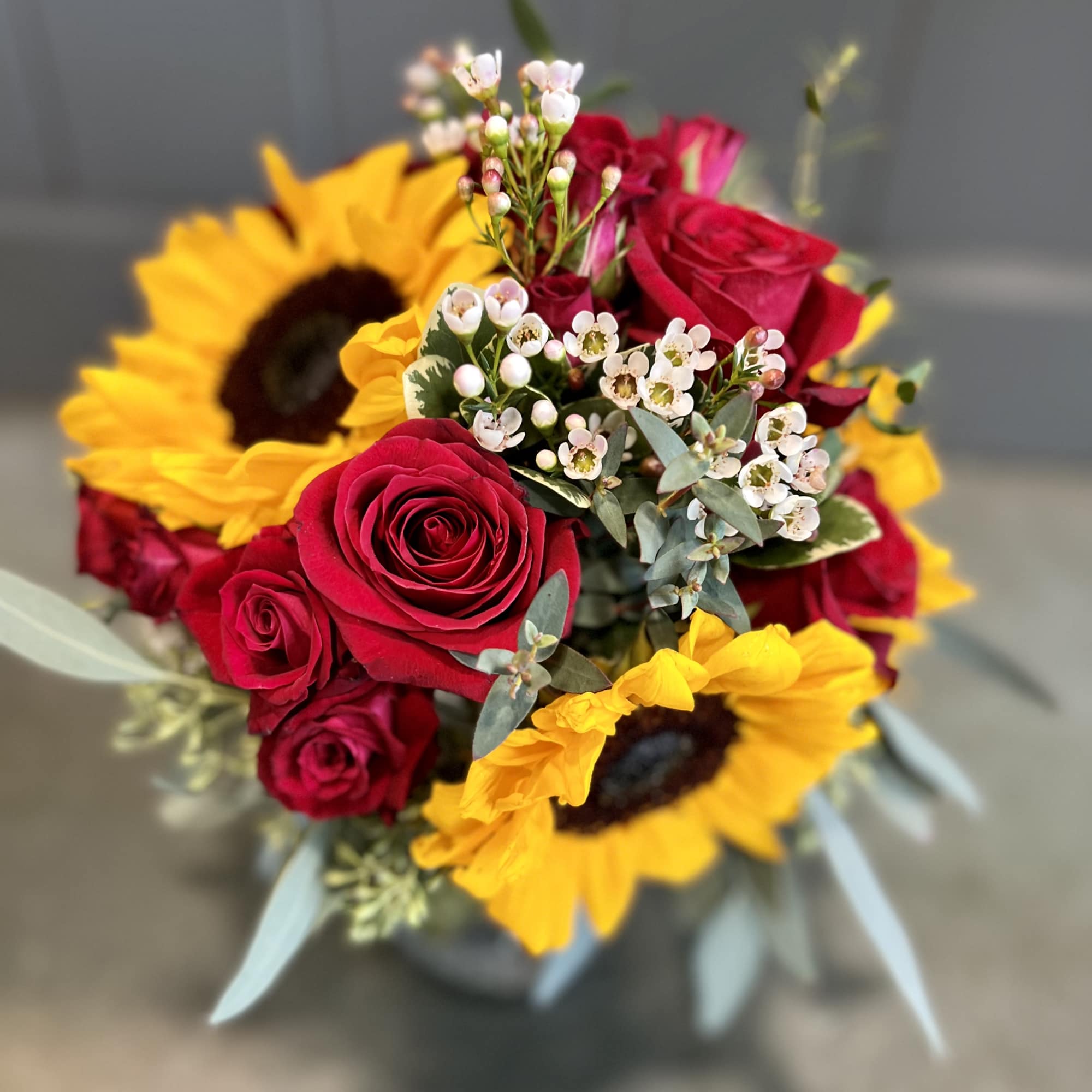 Sunflowers and red roses in small vase.