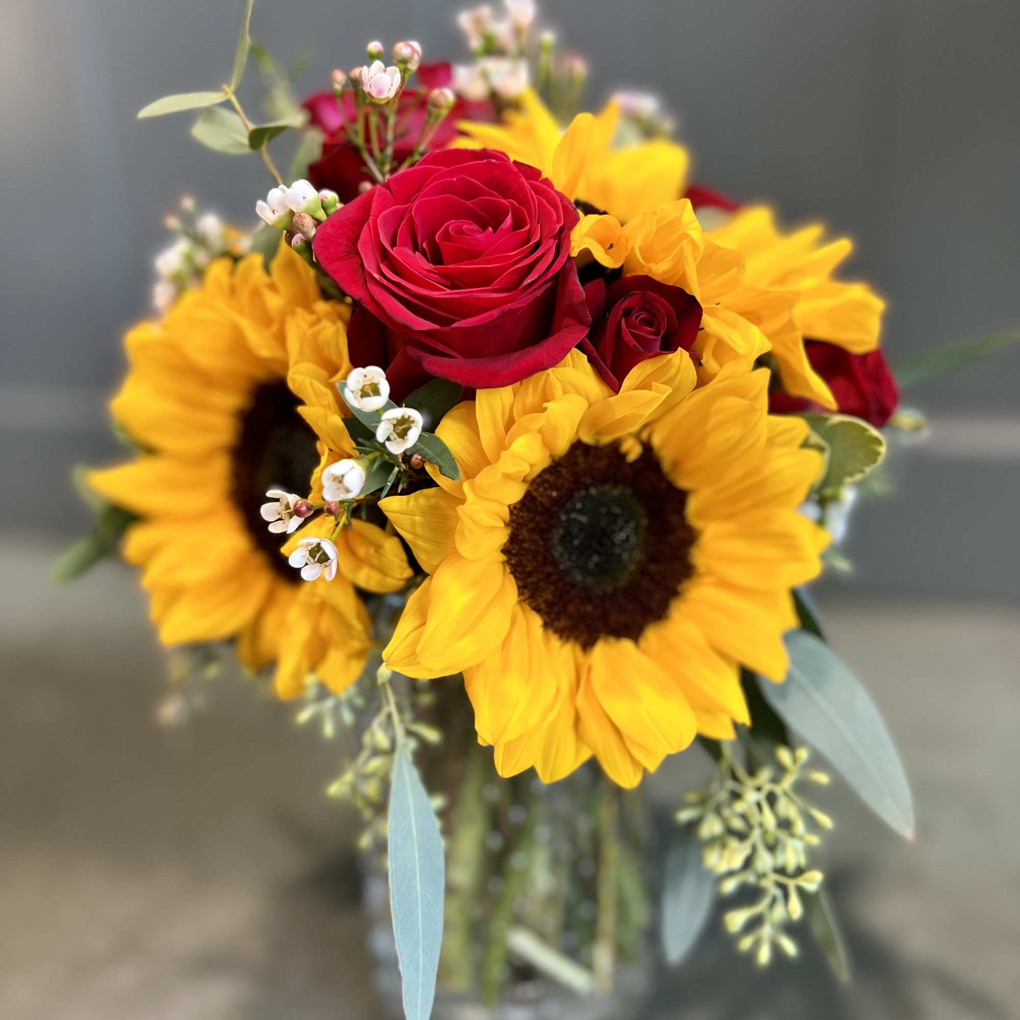 Sunflowers and red roses in small vase.