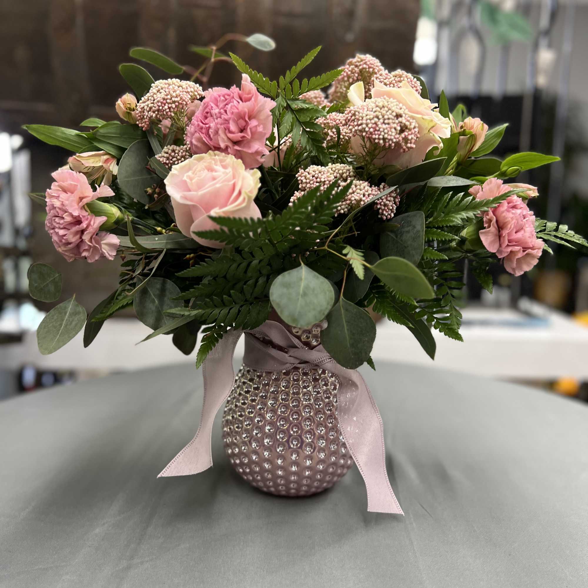 Pink roses and carnations in a beaded vase with a ribbon