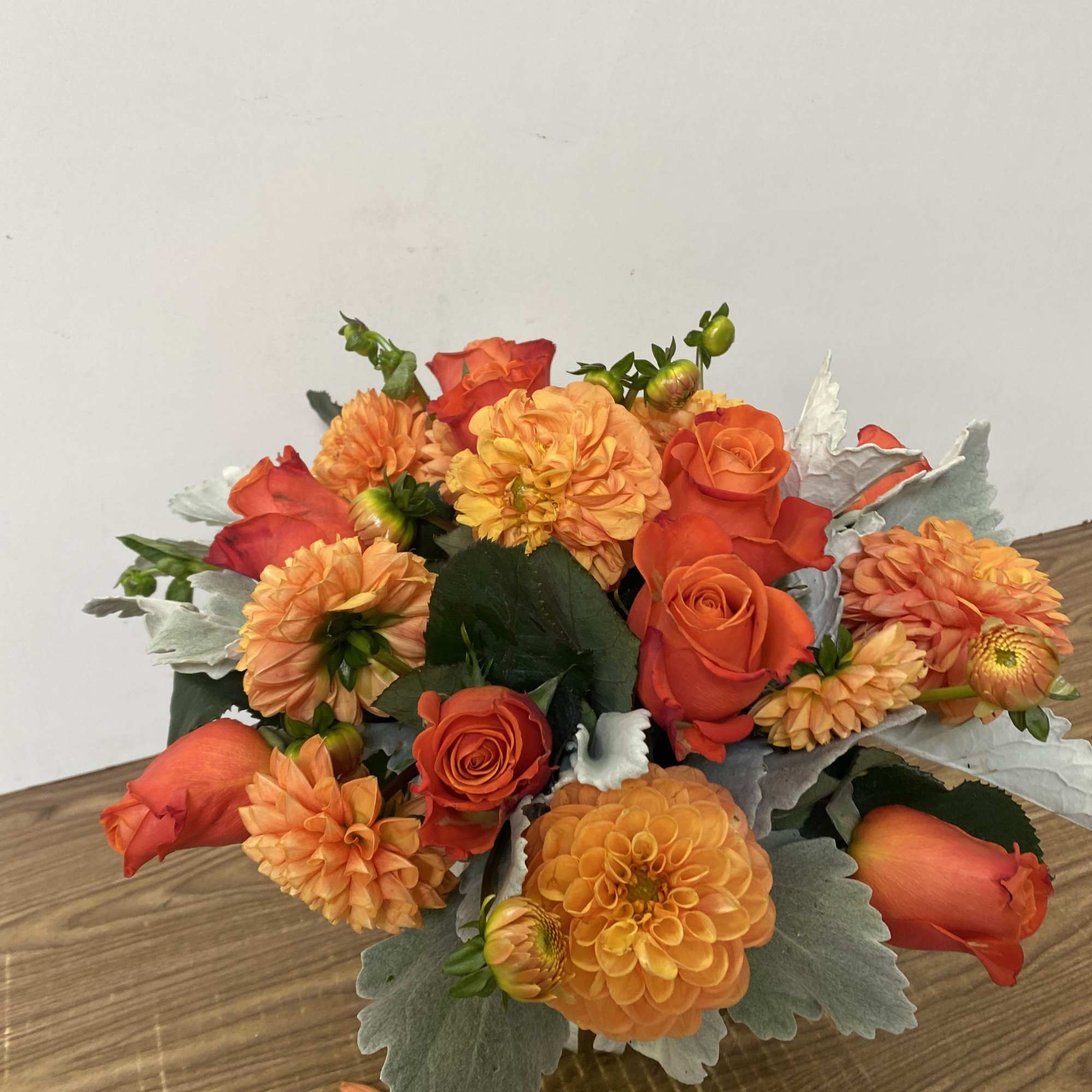 In a glass vase combinations of orange dollar and orange roses