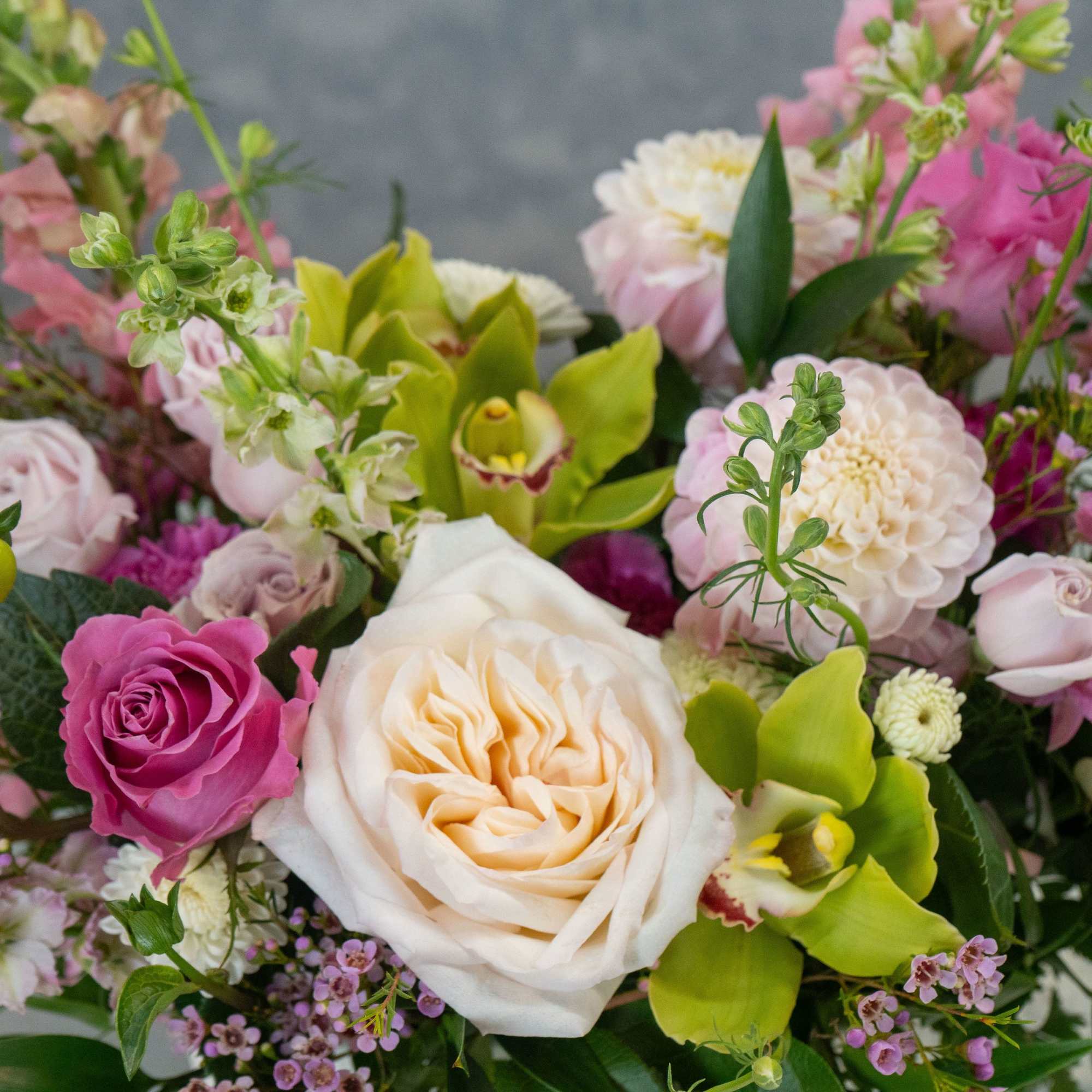 Cream and blush roses mingle with bright green orchids and tall spires