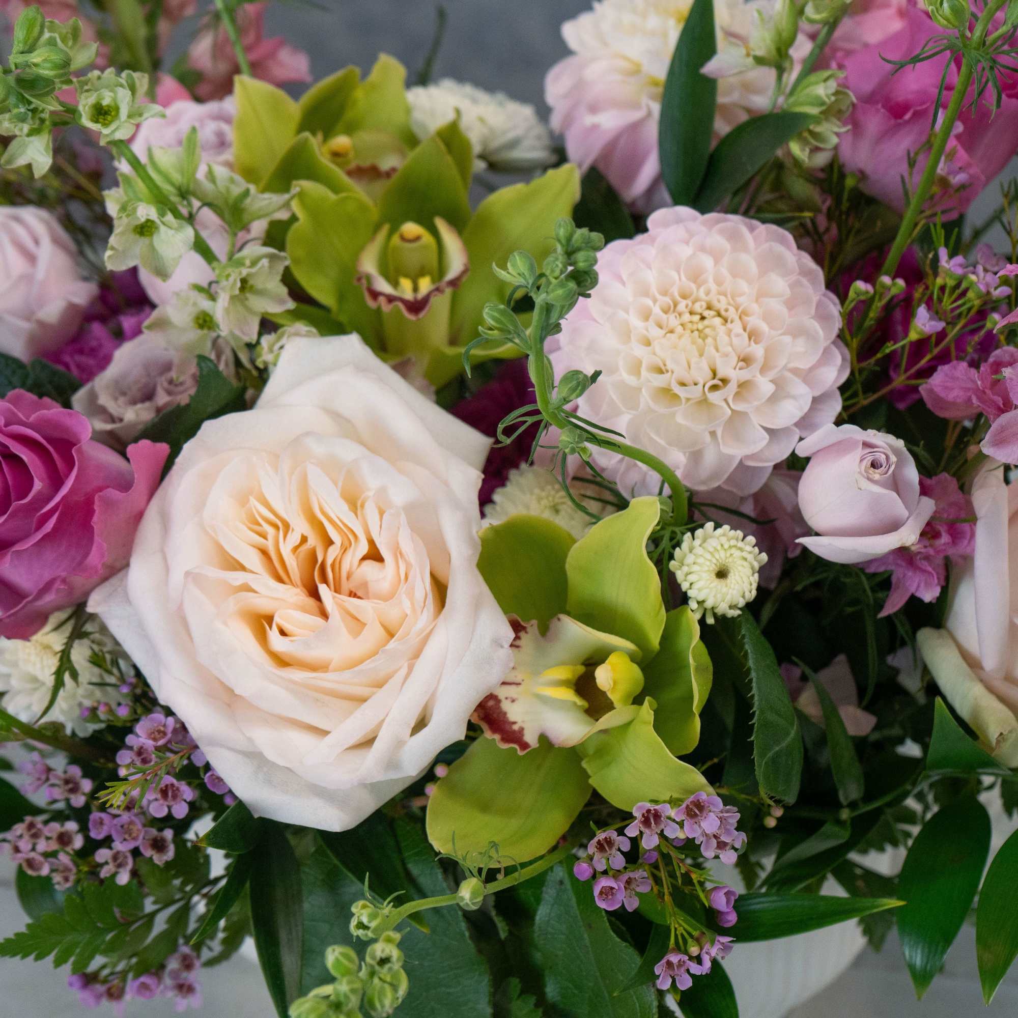 Cream and blush roses mingle with bright green orchids and tall spires