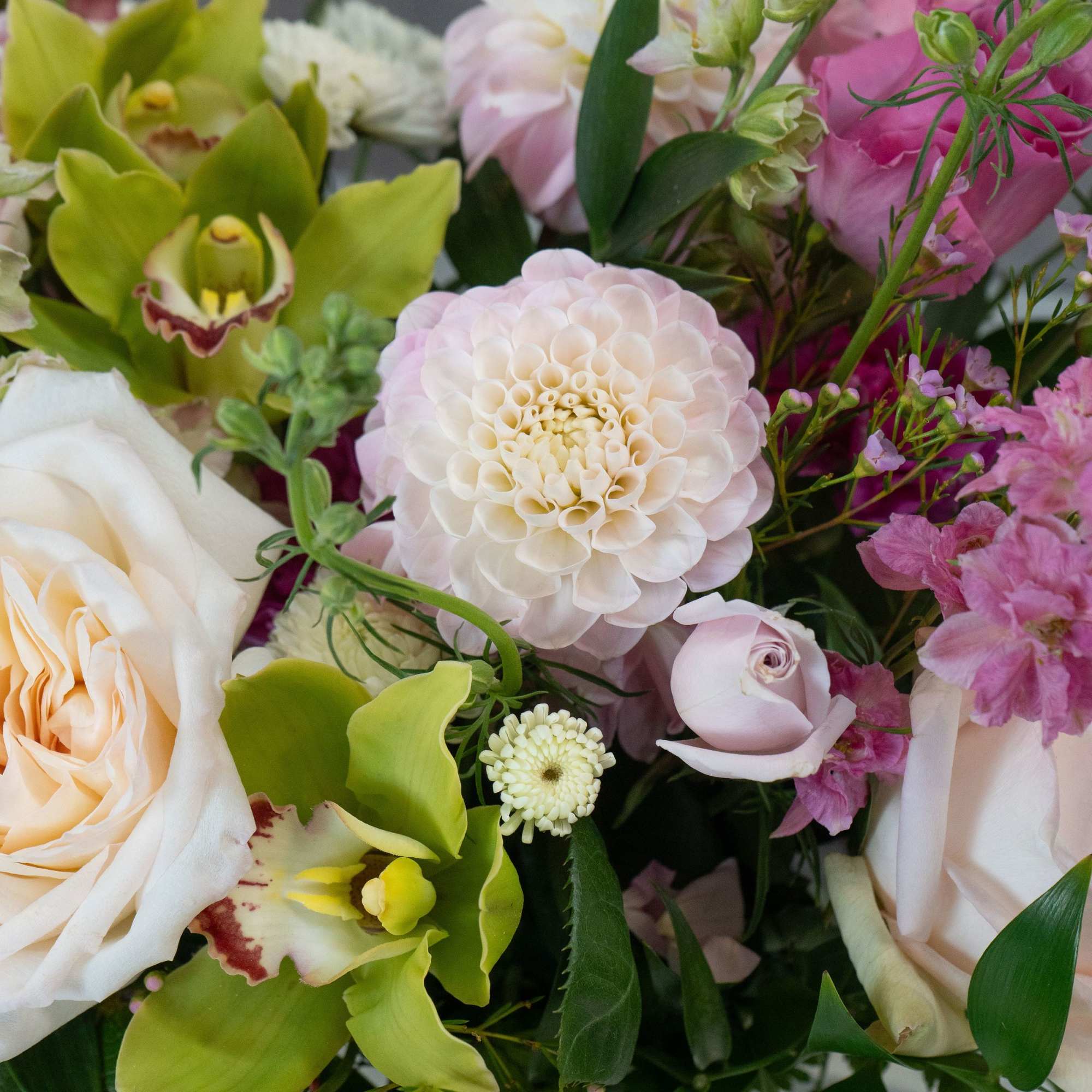Cream and blush roses mingle with bright green orchids and tall spires