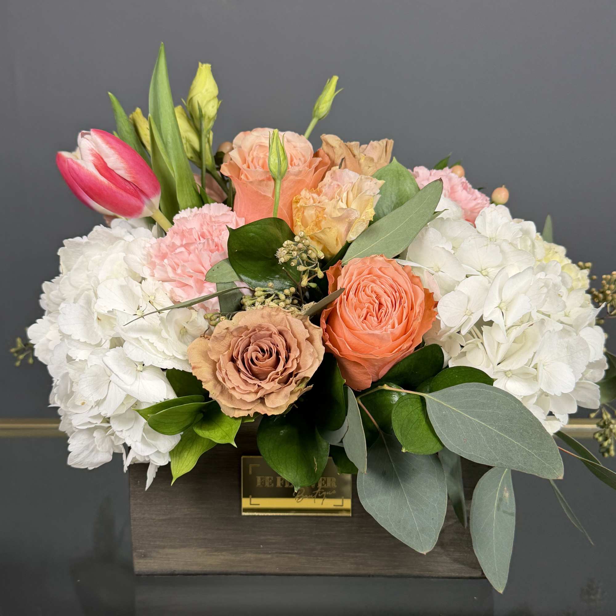 A romantic combination of peach roses, pink tulips, and delicate textures, designed
