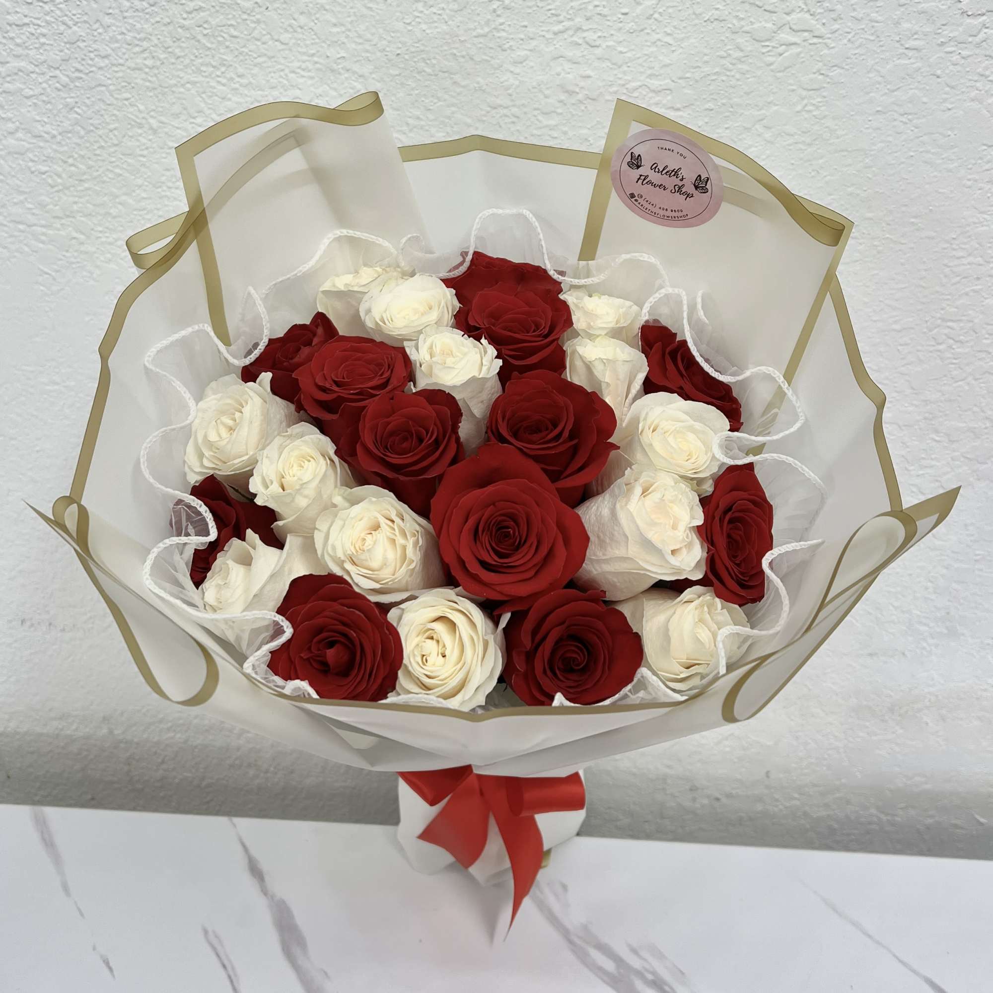 Bouquet of red and white roses wrapped in clear paper with a red ribbon